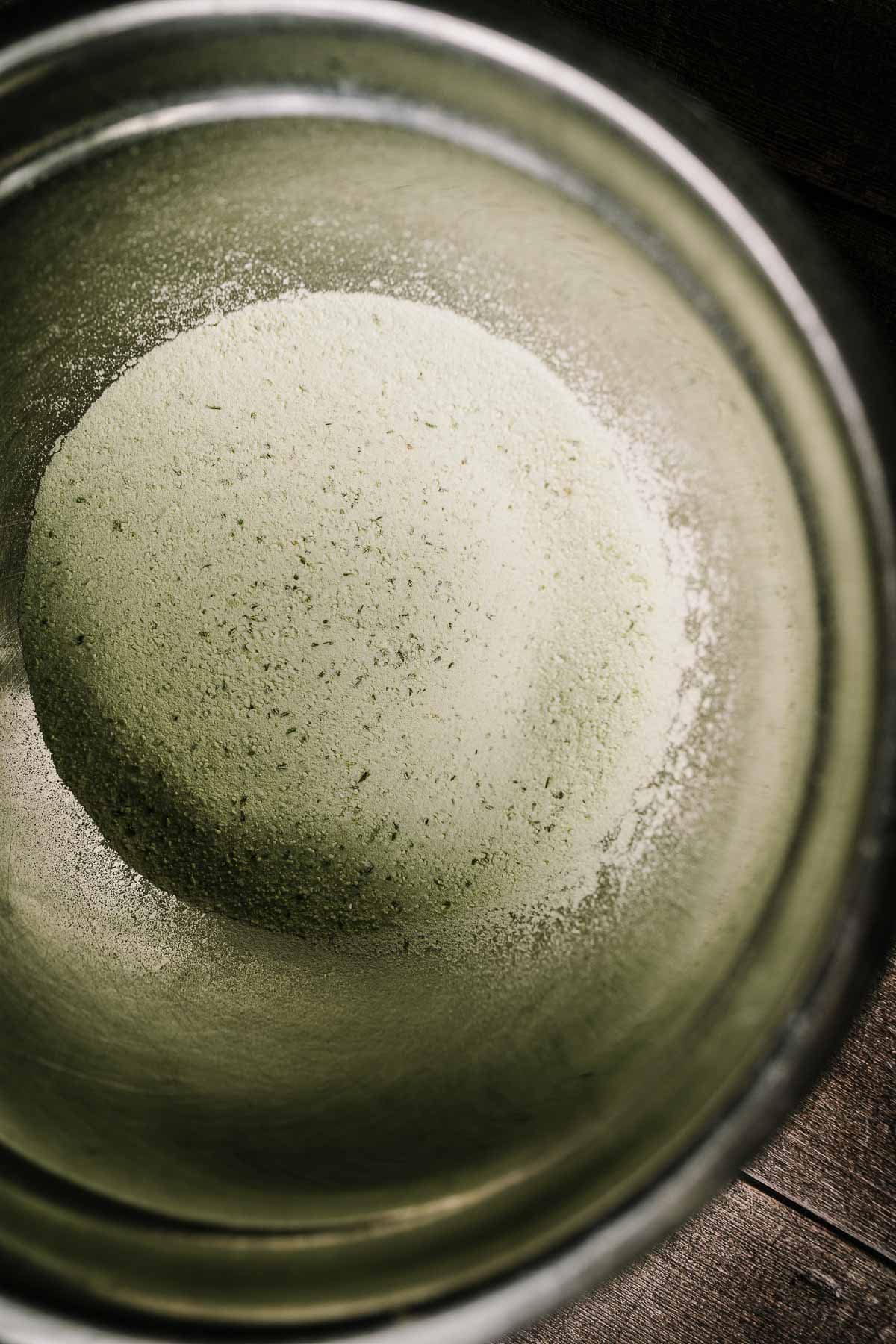 A silver mixing bowl filled with rosemary salt.