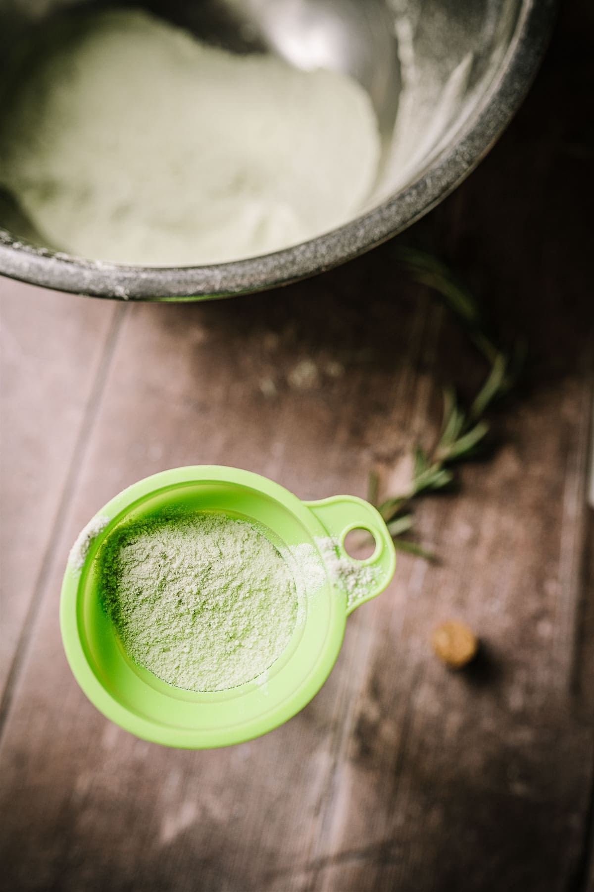 A green silicone funnel filled with green salt sticking out of a glass bottle.