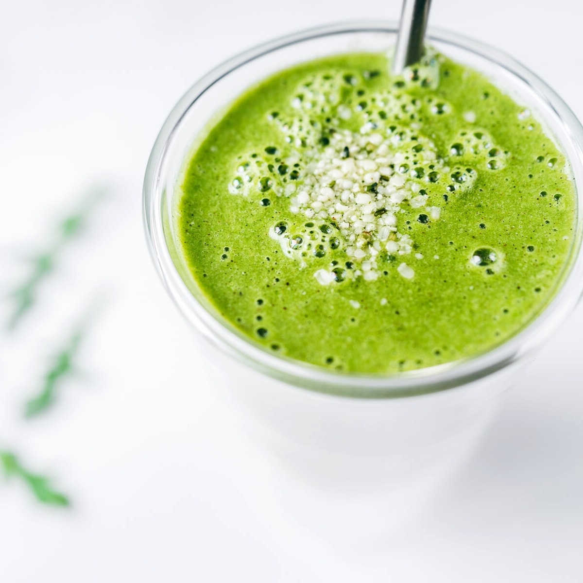 Close shot of a bright green smoothie in a large glass.