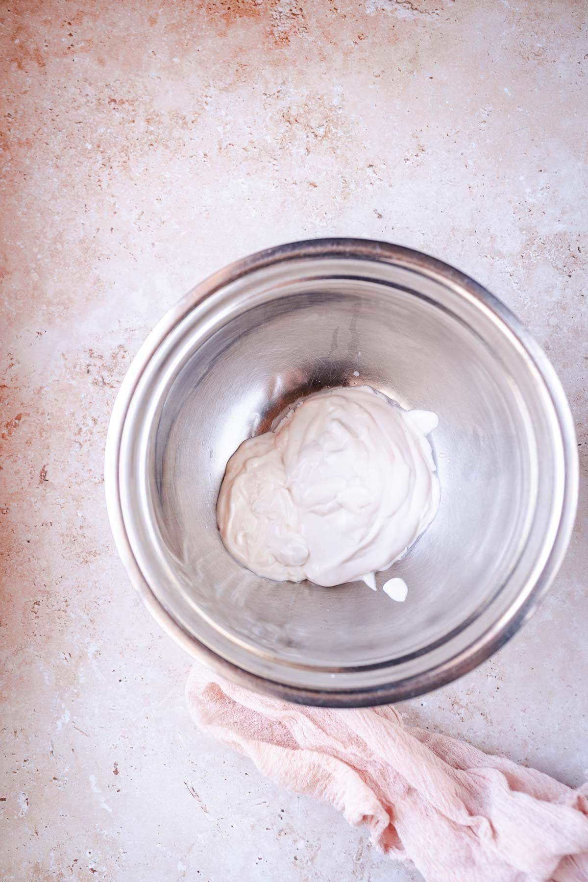 A silver mixing bowl filled with creamy white yogurt.