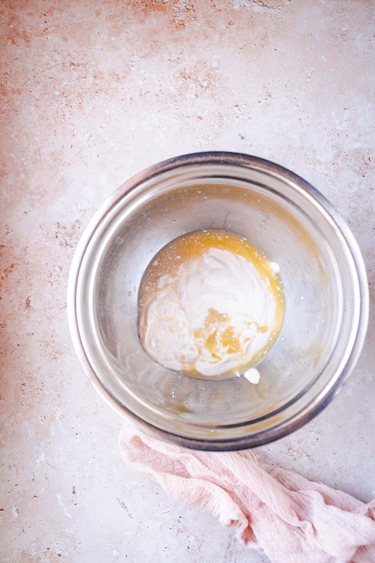 A silver mixing bowl filled with white and yellow liquid ingredients.