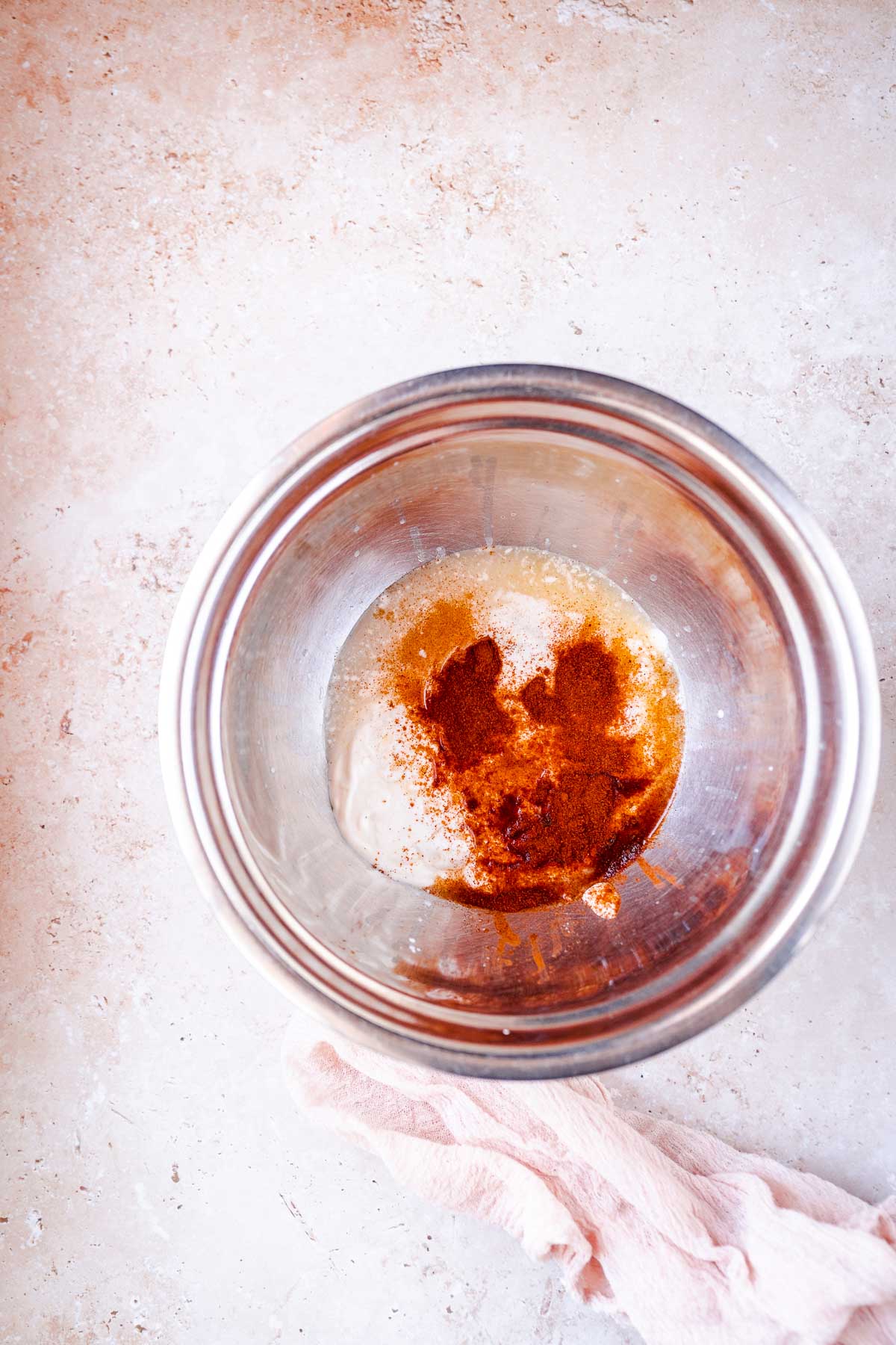 Red spices scattered on top of other ingredients in a silver mixing bowl.