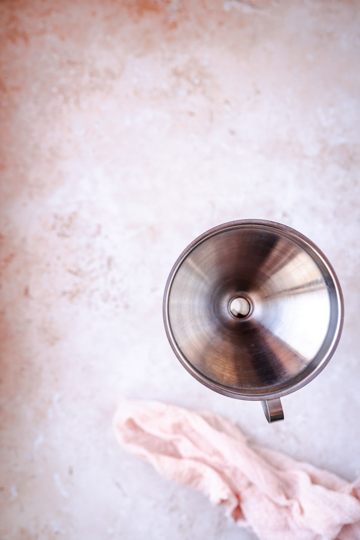 A silver metal funnel juts out of a clear glass bottle.