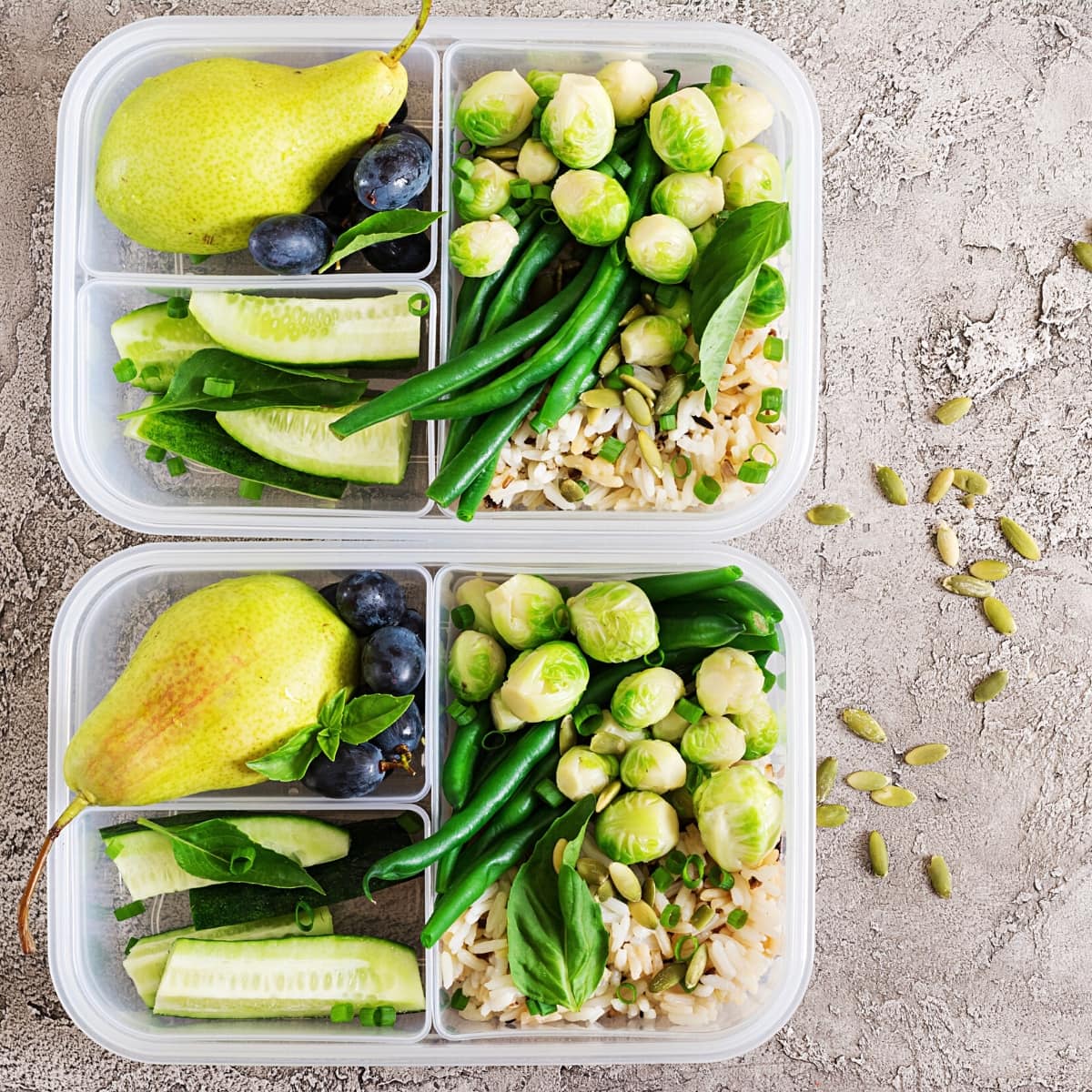 Two clear meal prep storage boxes filled with brown rice, veggies and fruit.