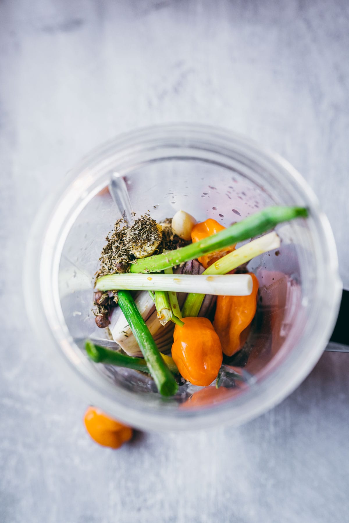 An open blender container filled with veggies and spices.