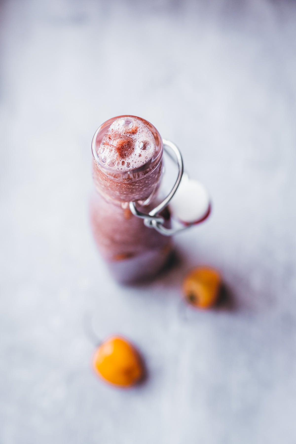 An open glass bottle filled with a bubbly homemade hot sauce.