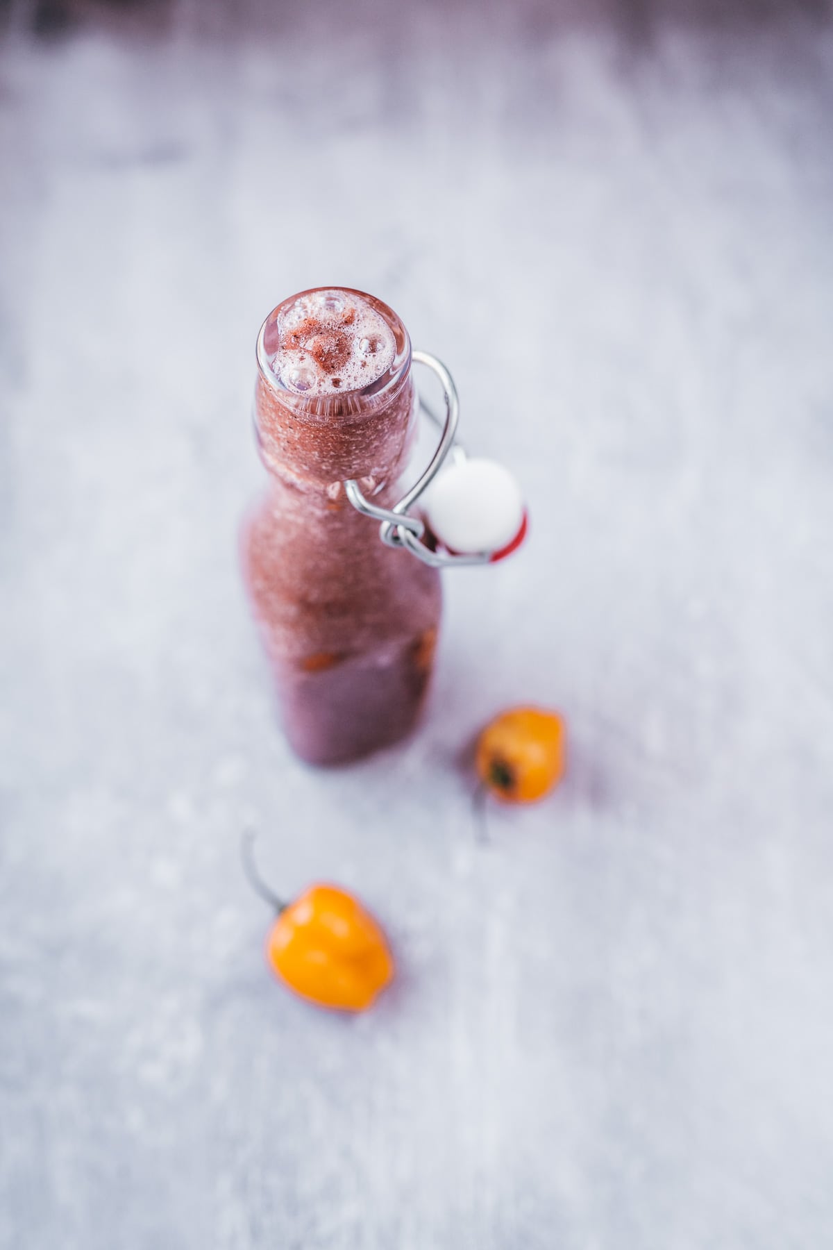 An open glass bottle bubbling over with a dark purple sauce.