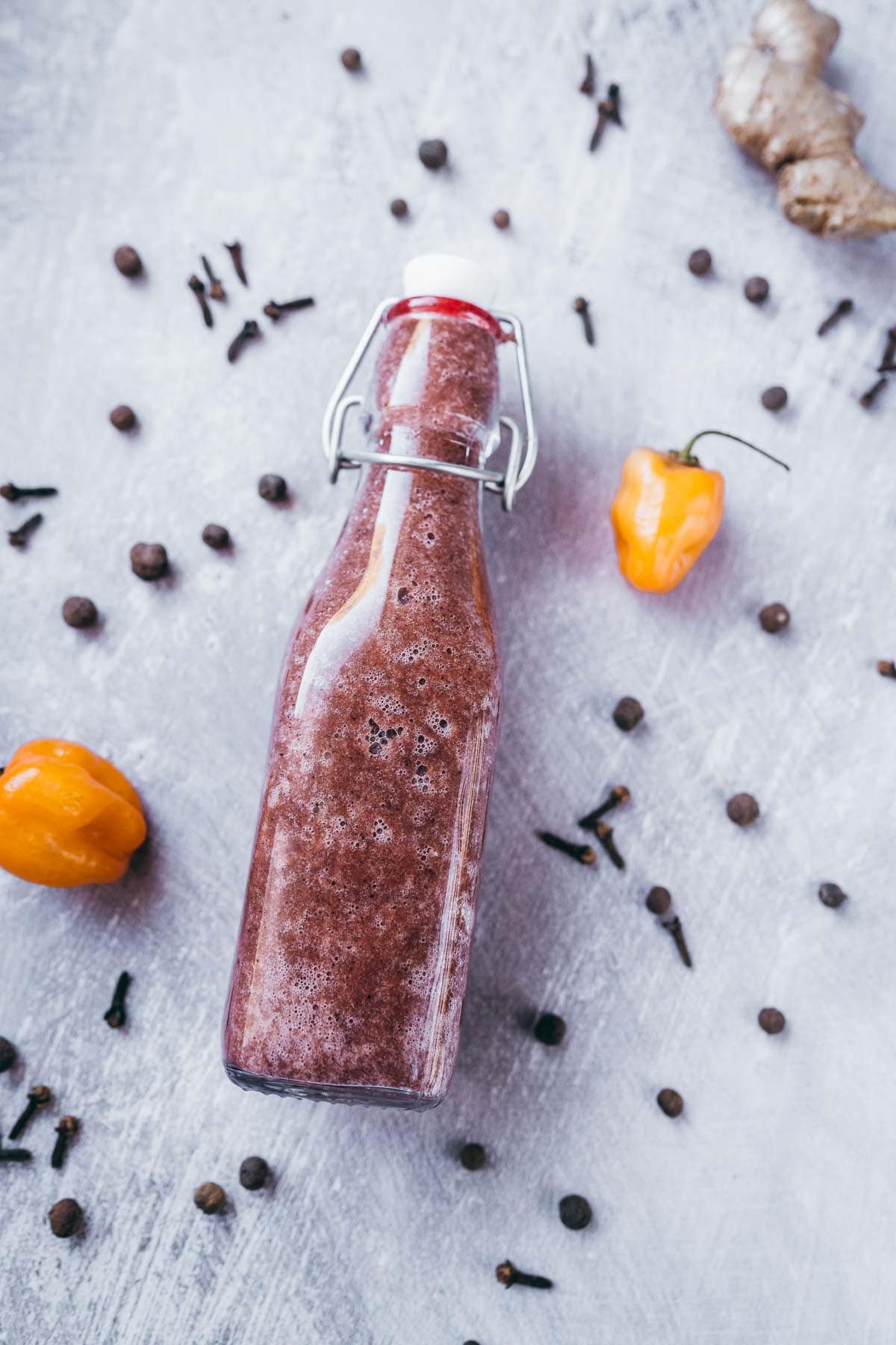 A clear glass swing-top bottle filled with a dark brown sauce.