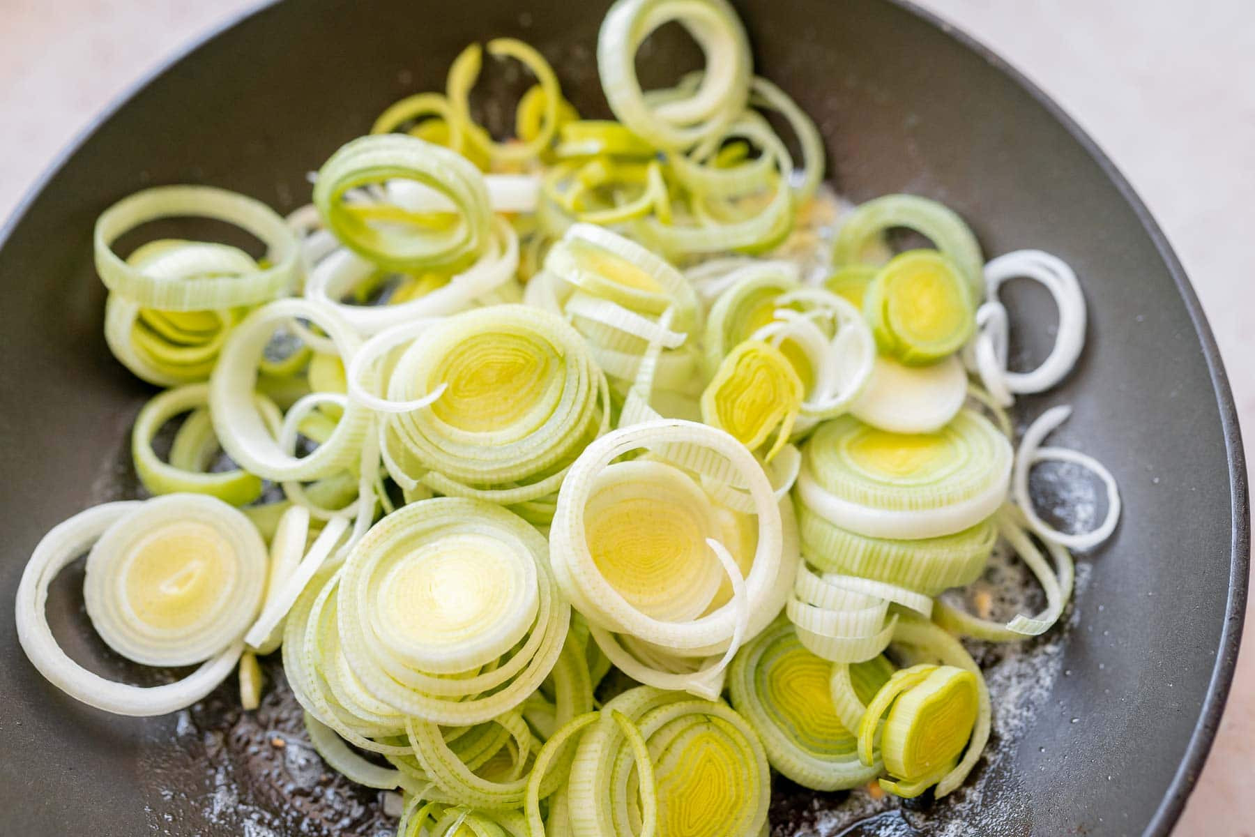 A skillet filled with sliced raw leeks.