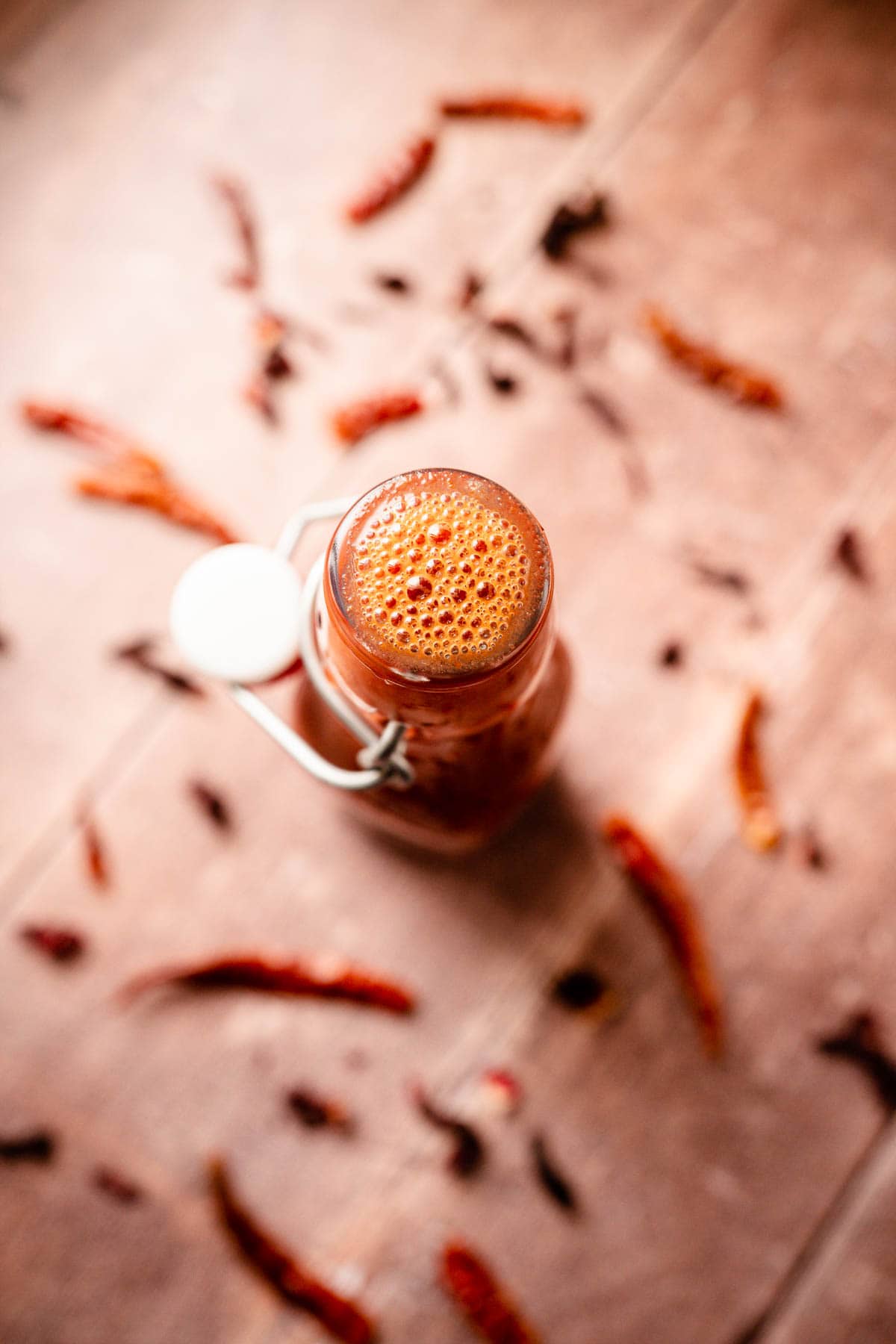 Top shot of a glass bottle of freshly blended red hot sauce.