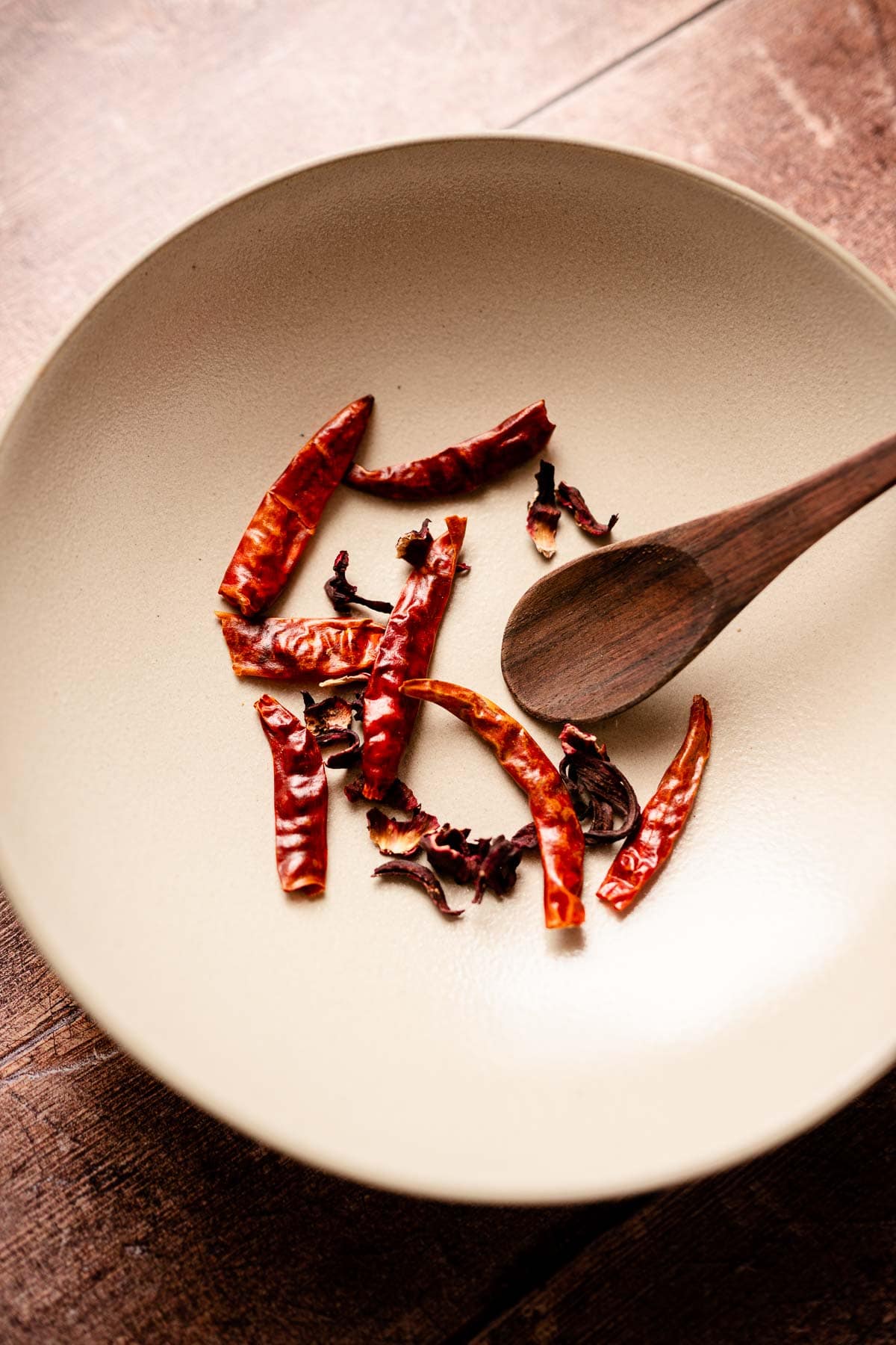 A bowl filled with hibiscus flowers and dried Thai chilies.