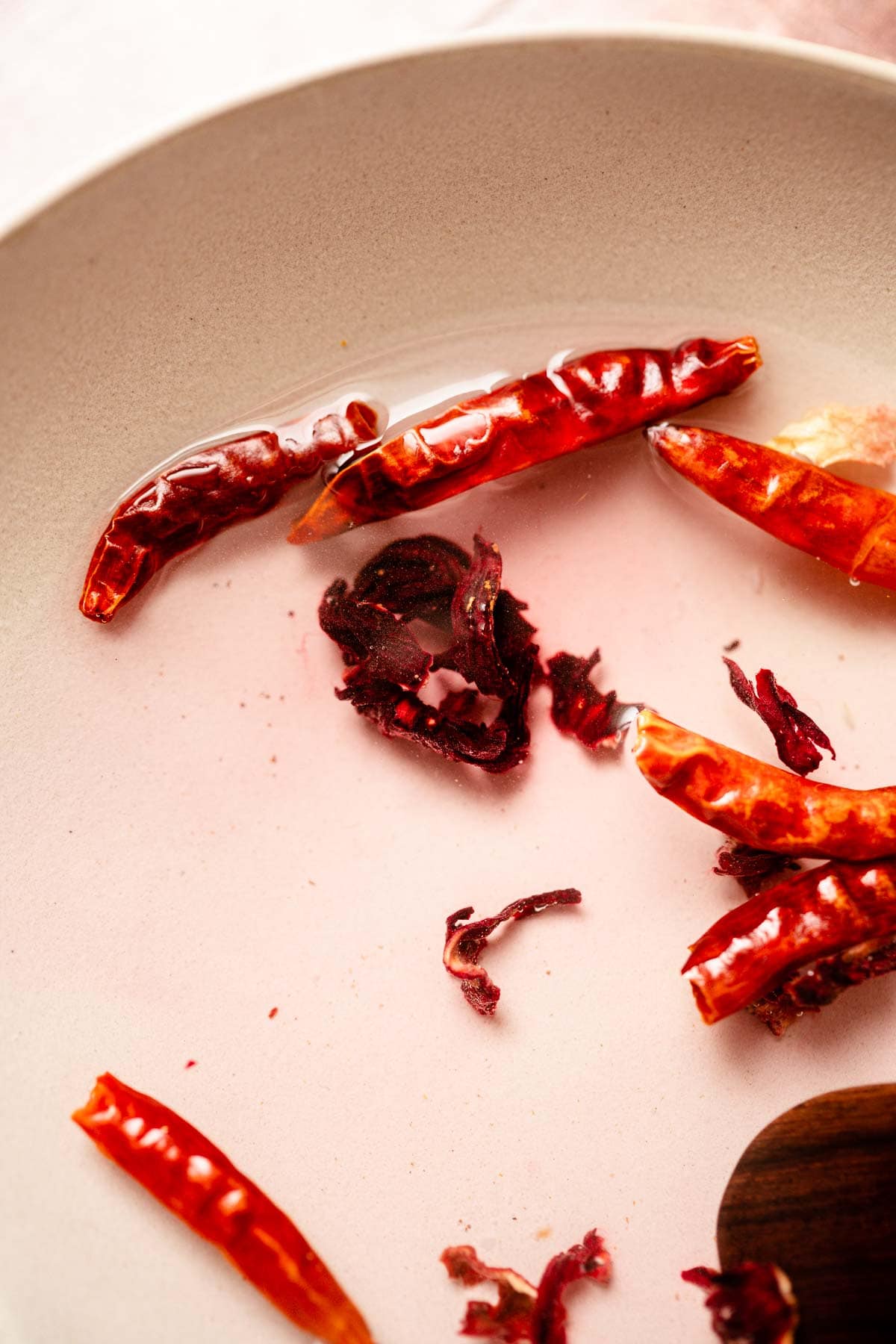 Dried peppers and flowers resting in a bowl of water.