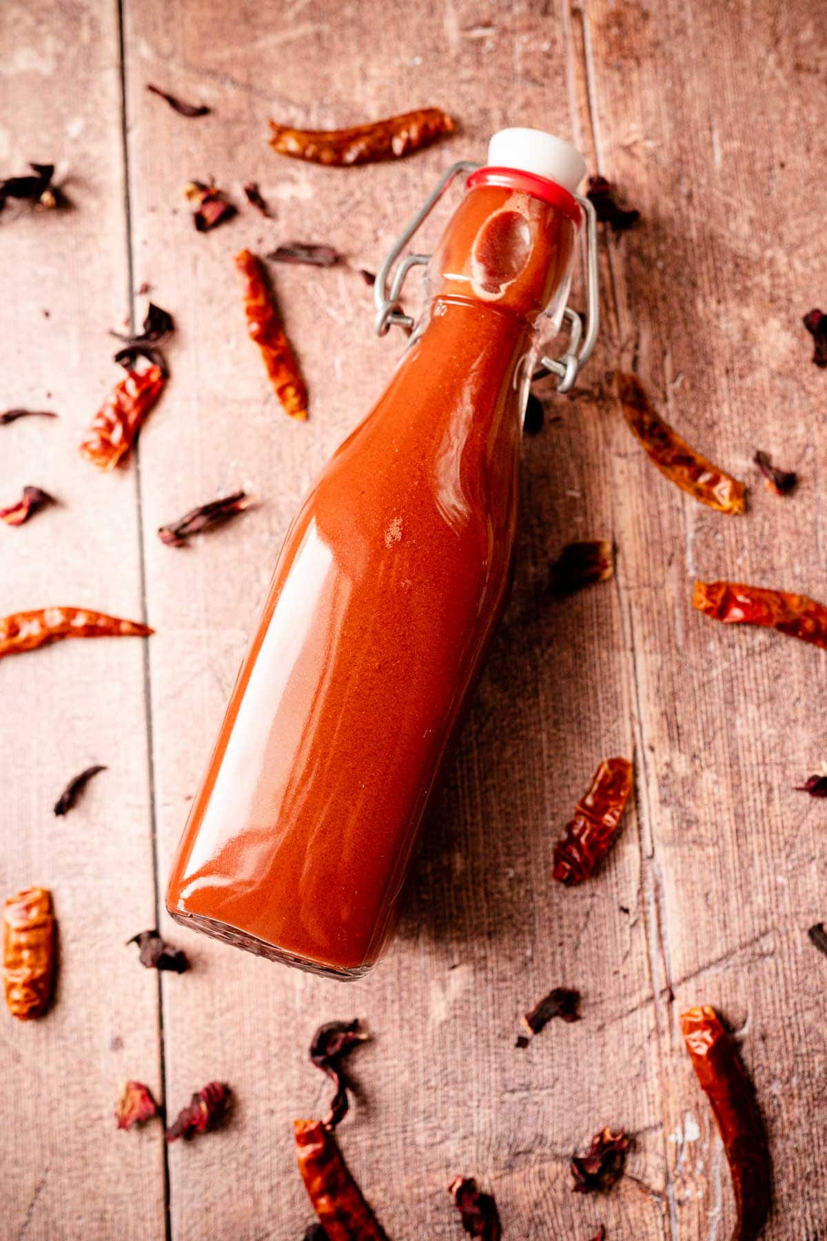 A clear glass red hot sauce bottle filled with a red sauce.