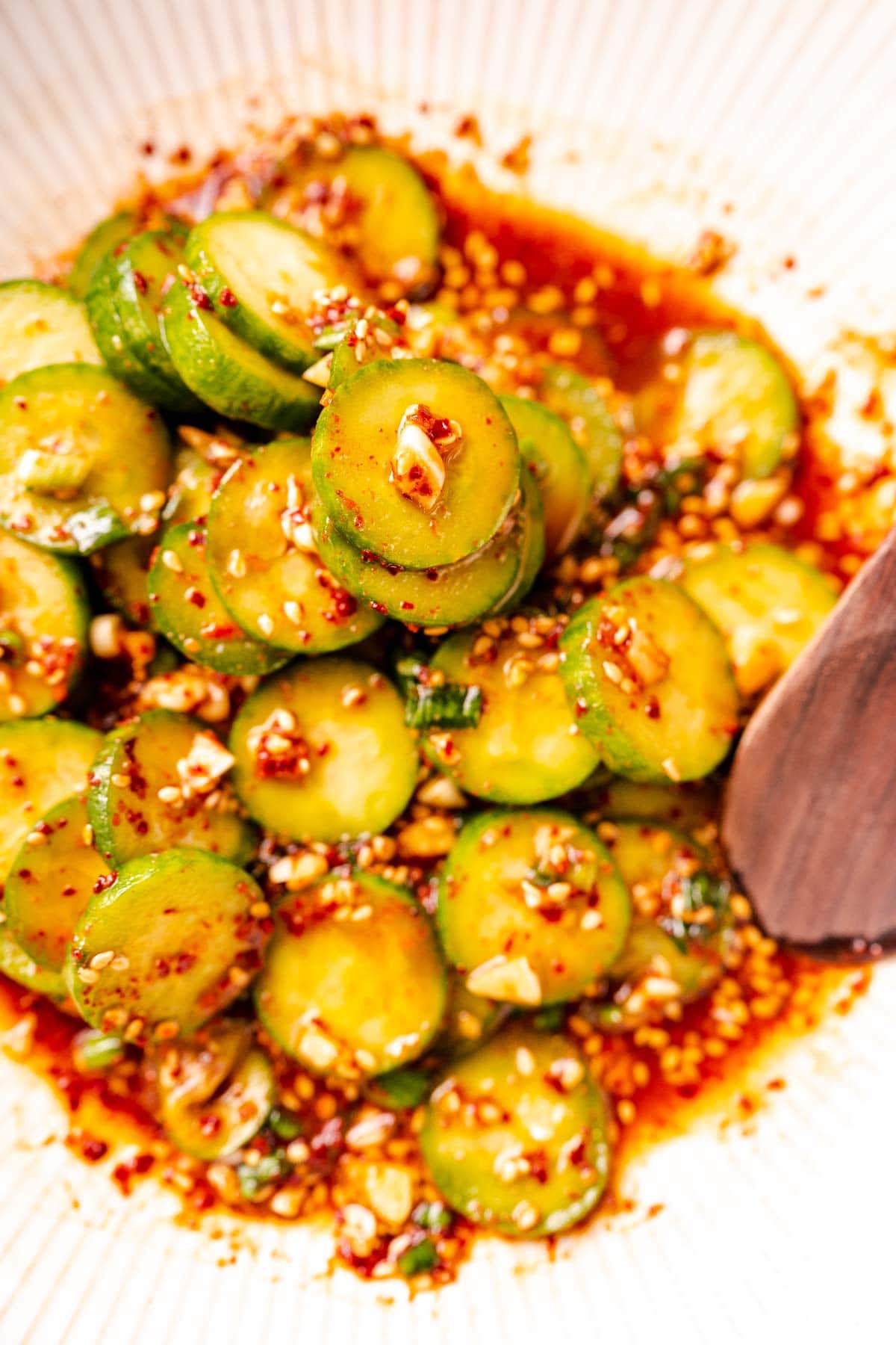 Close shots of cucumber slices drenched in a red dressing.