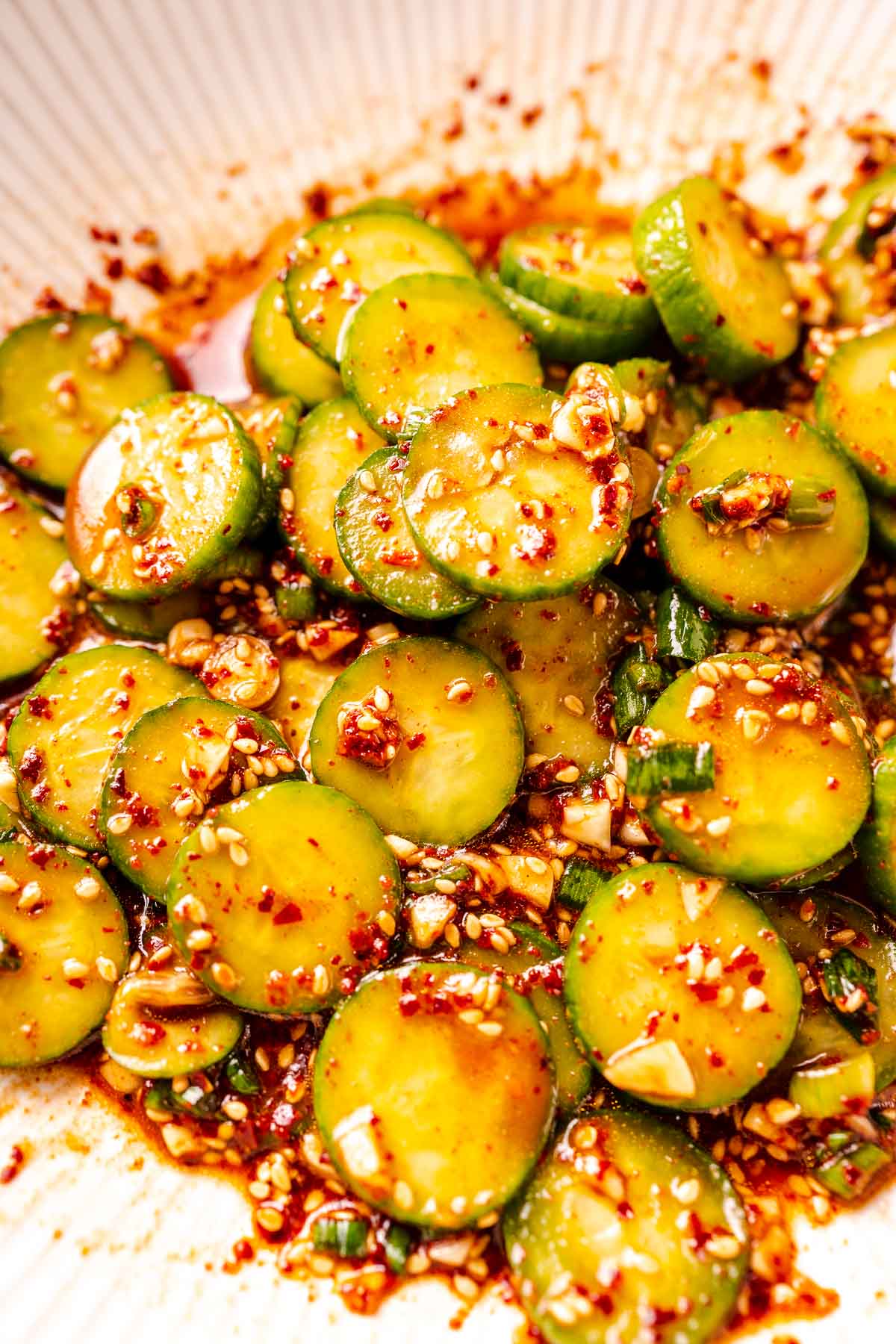 A cucumber salad with a vibrant red sauce.