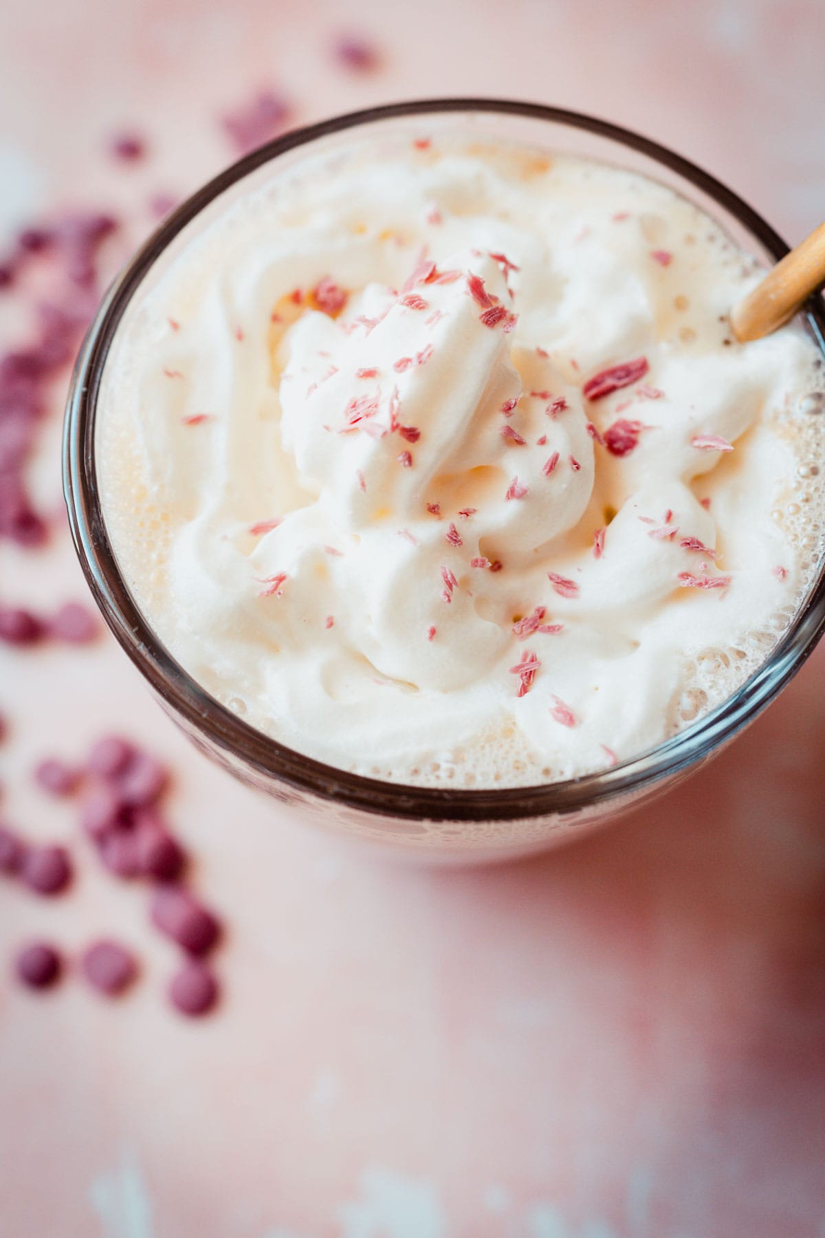 Top view of whipped cream and pink chocolate shavings in a mug.