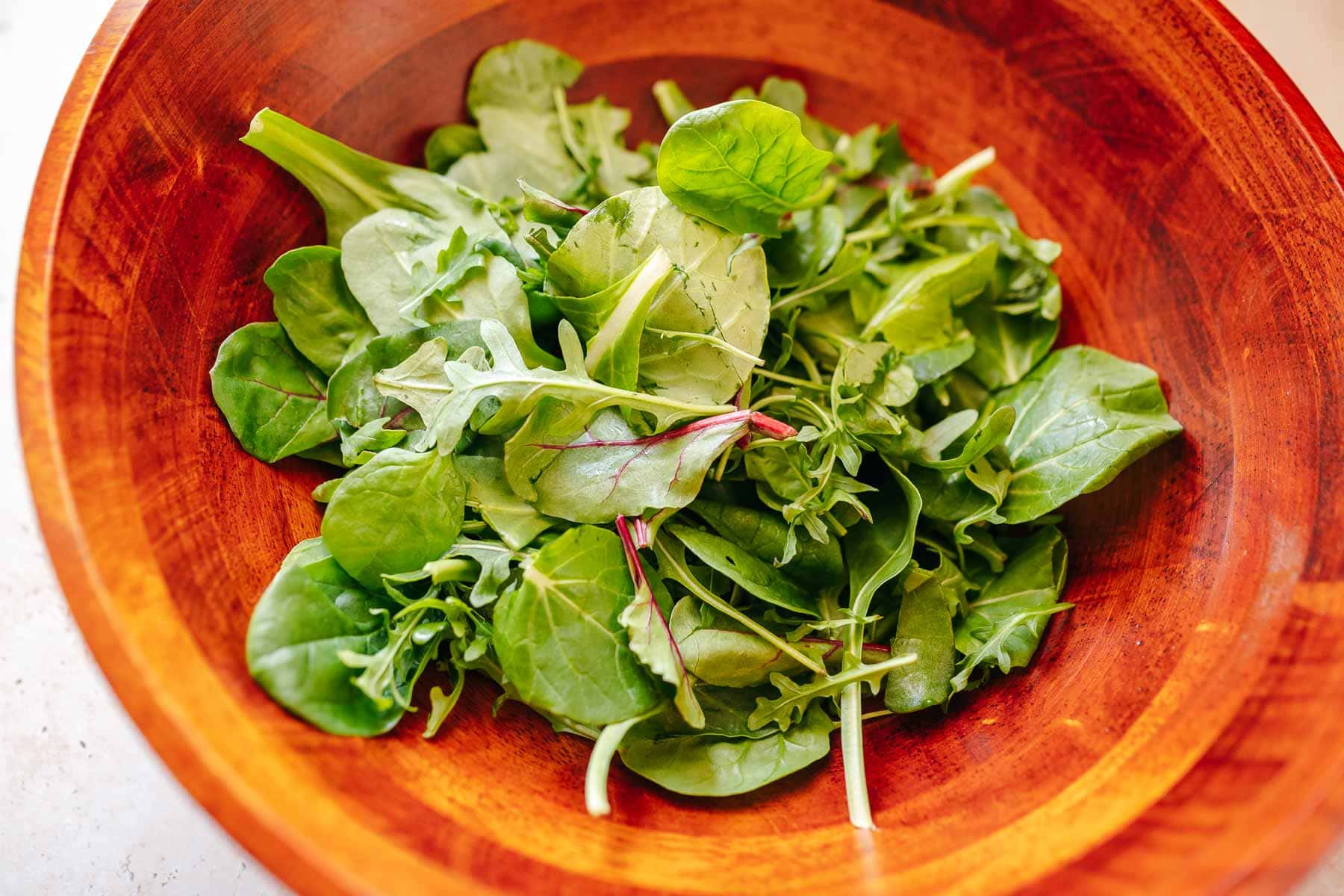 A wood salad bowl filled with fresh salad greens.