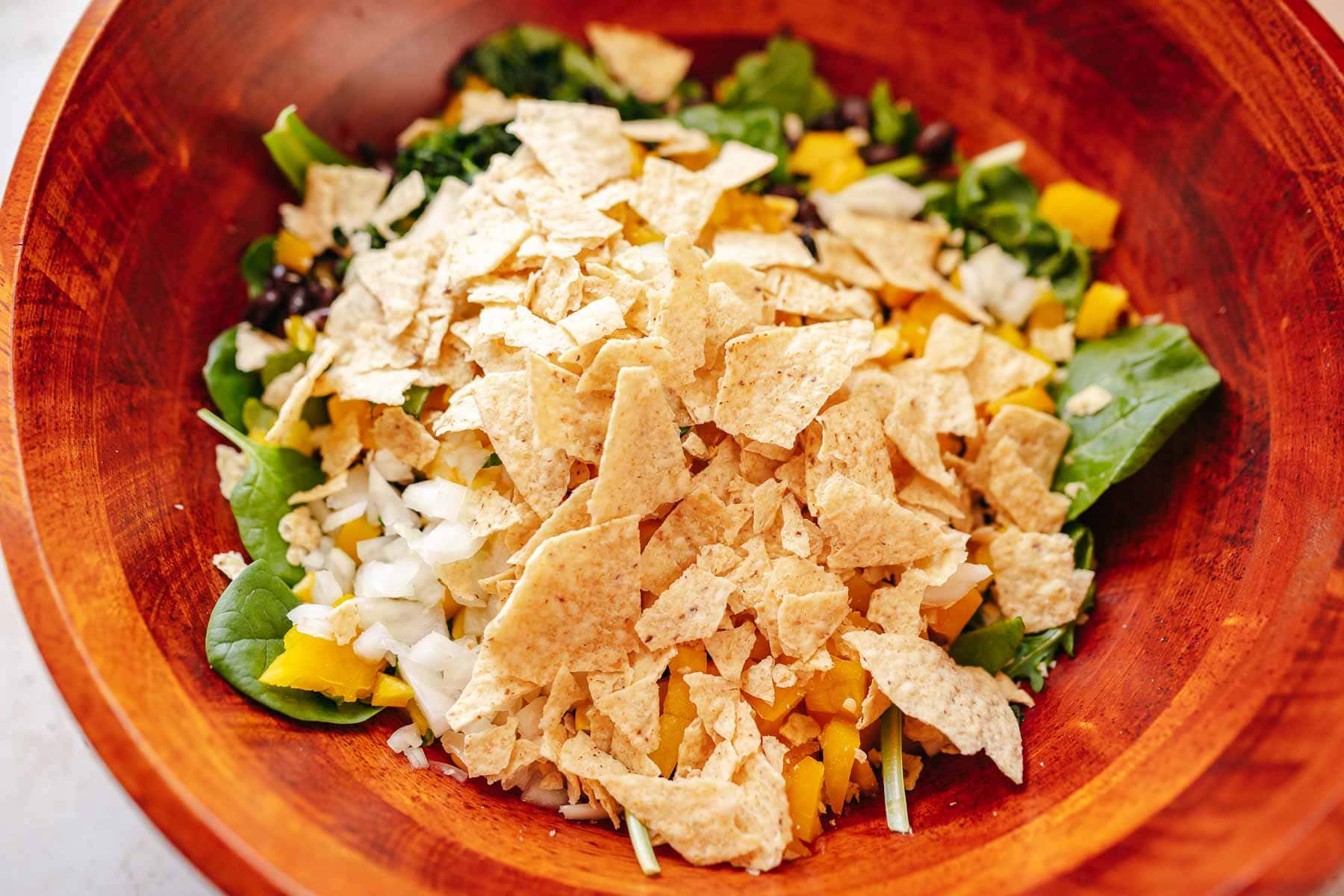 A large salad topped with crushed tortilla chips.