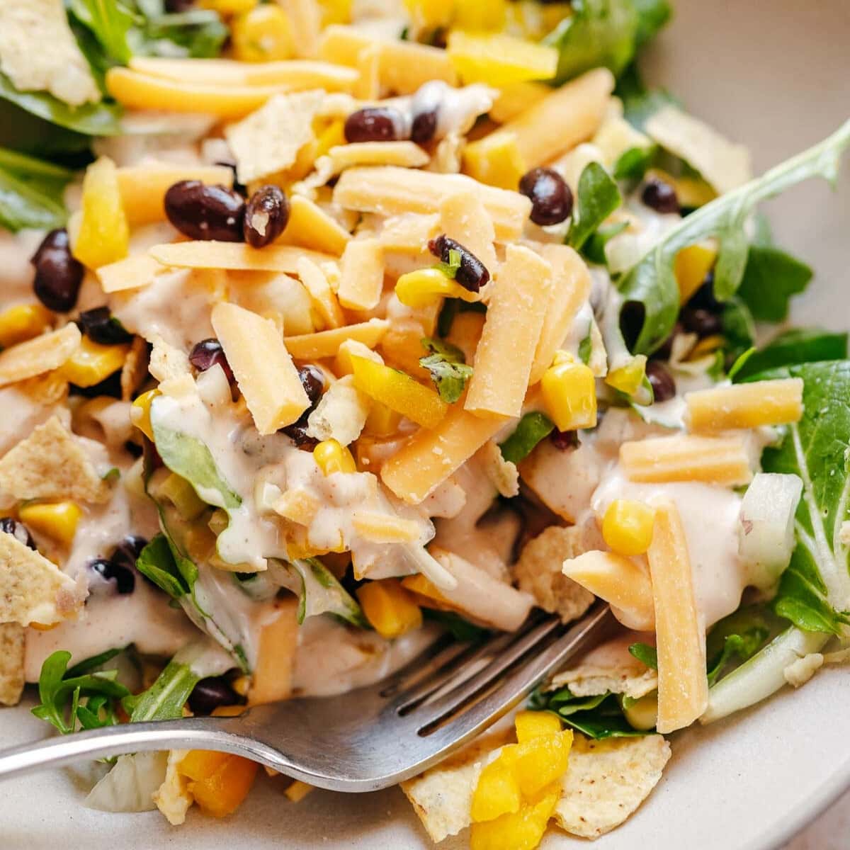 Close shot of a salad with cheese, beans, corn and creamy dressing