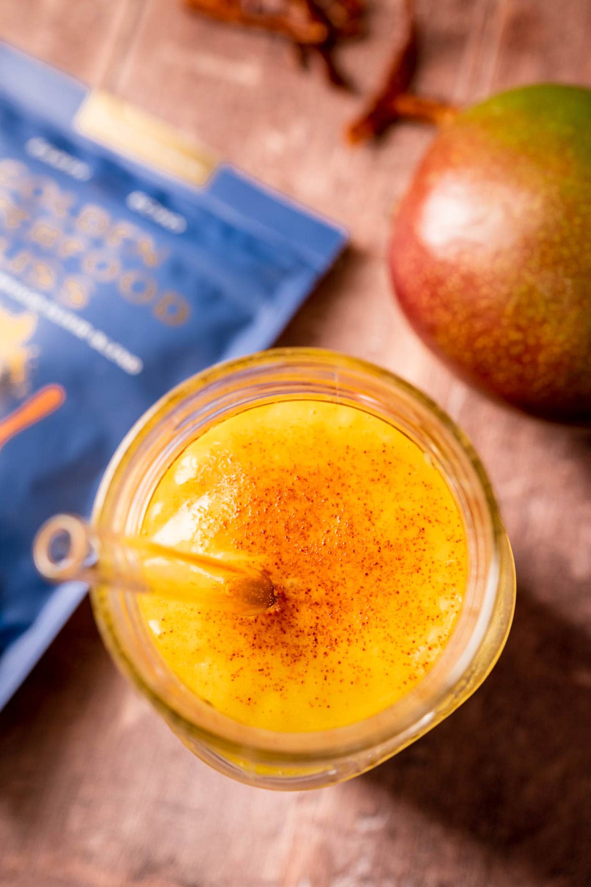 Close top view of a mango smoothie sprinkled with cayenne pepper.