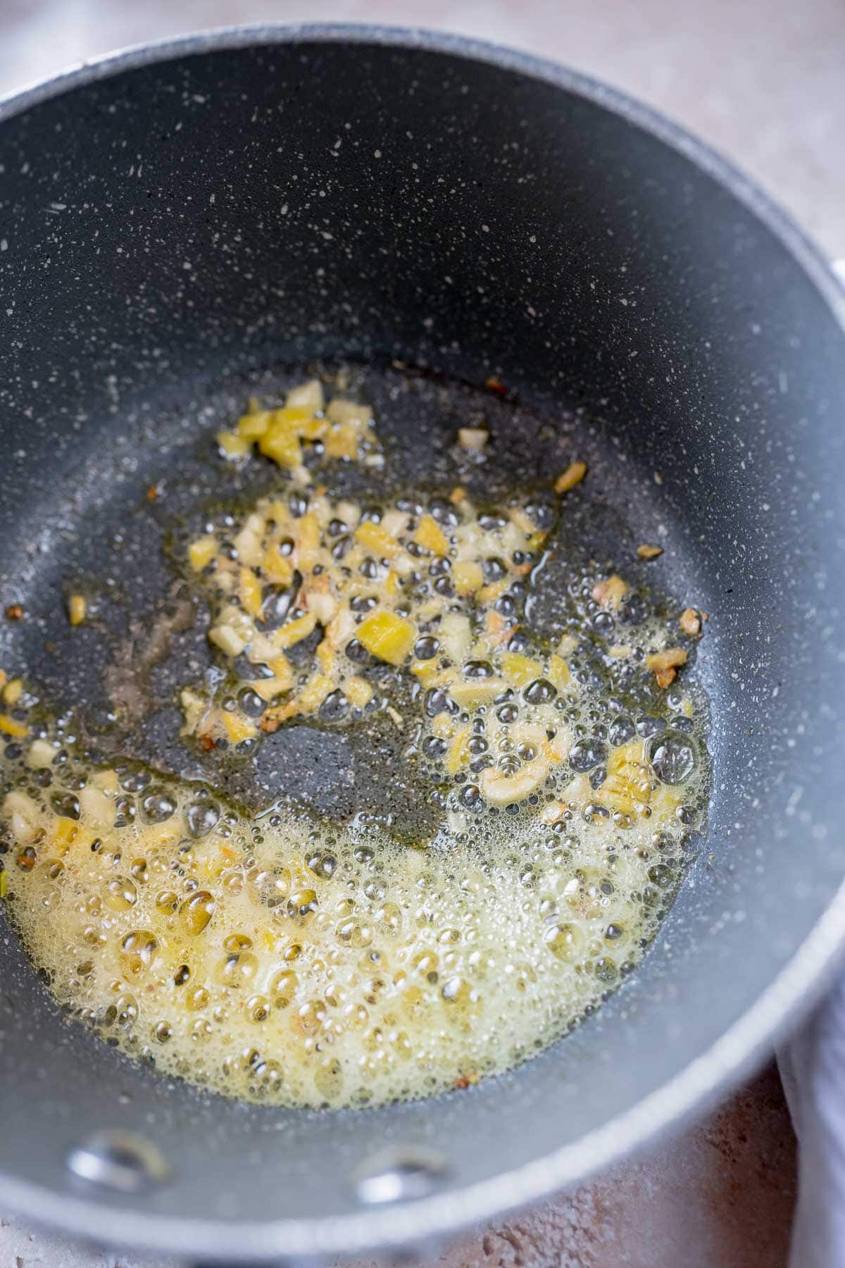 A saucepan with oil, ginger and garlic.