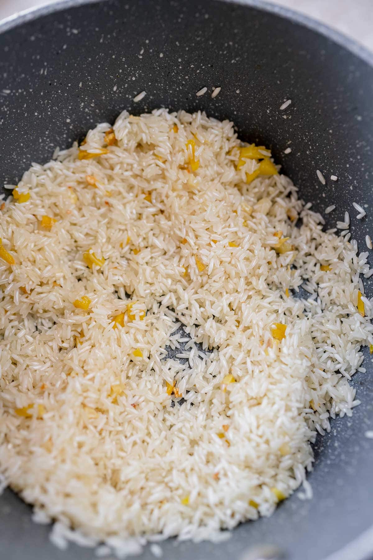 A saucepan with white rice. ginger and garlic.