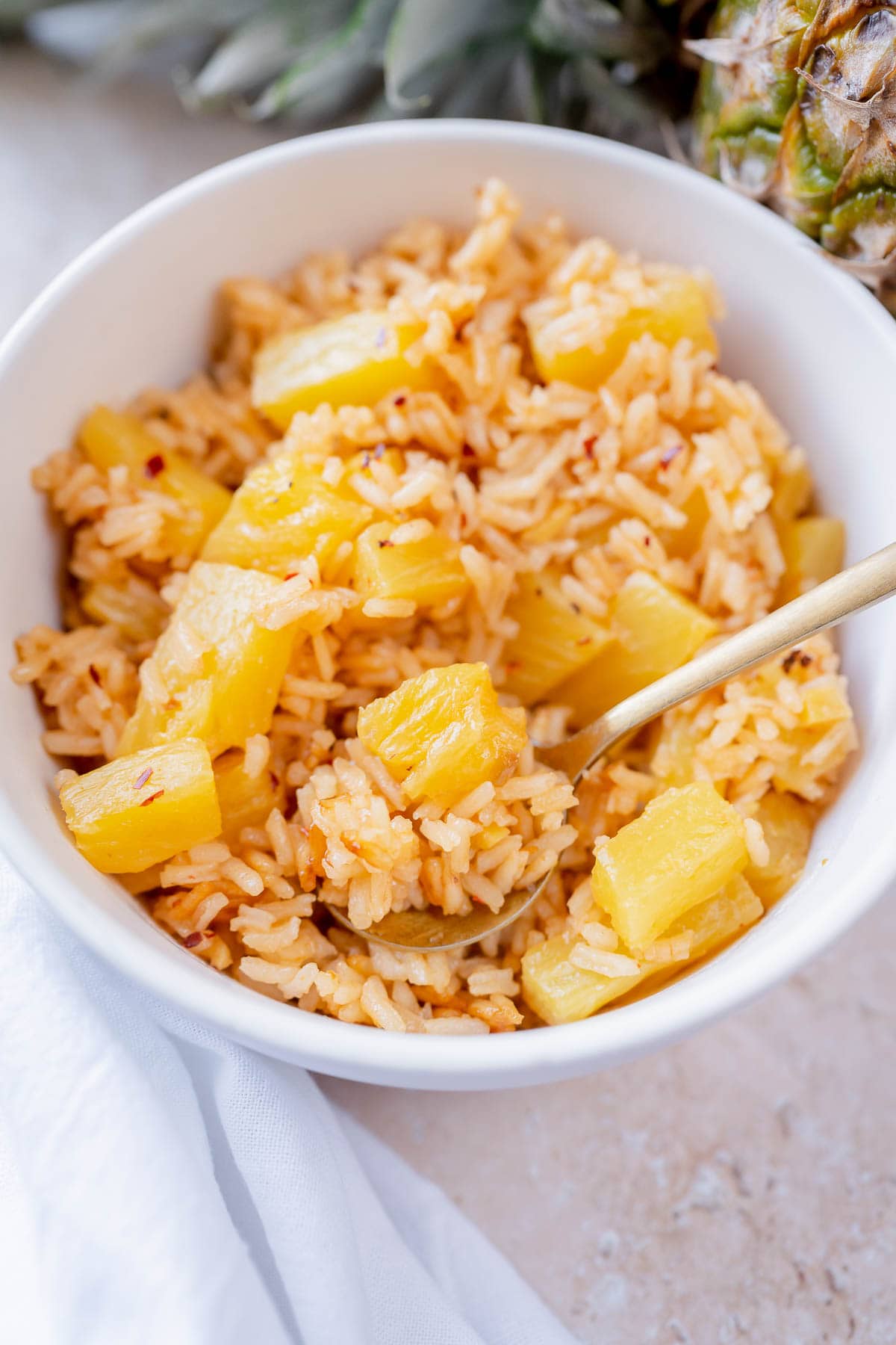 A white ceramic bowl filled with pineapple rice.