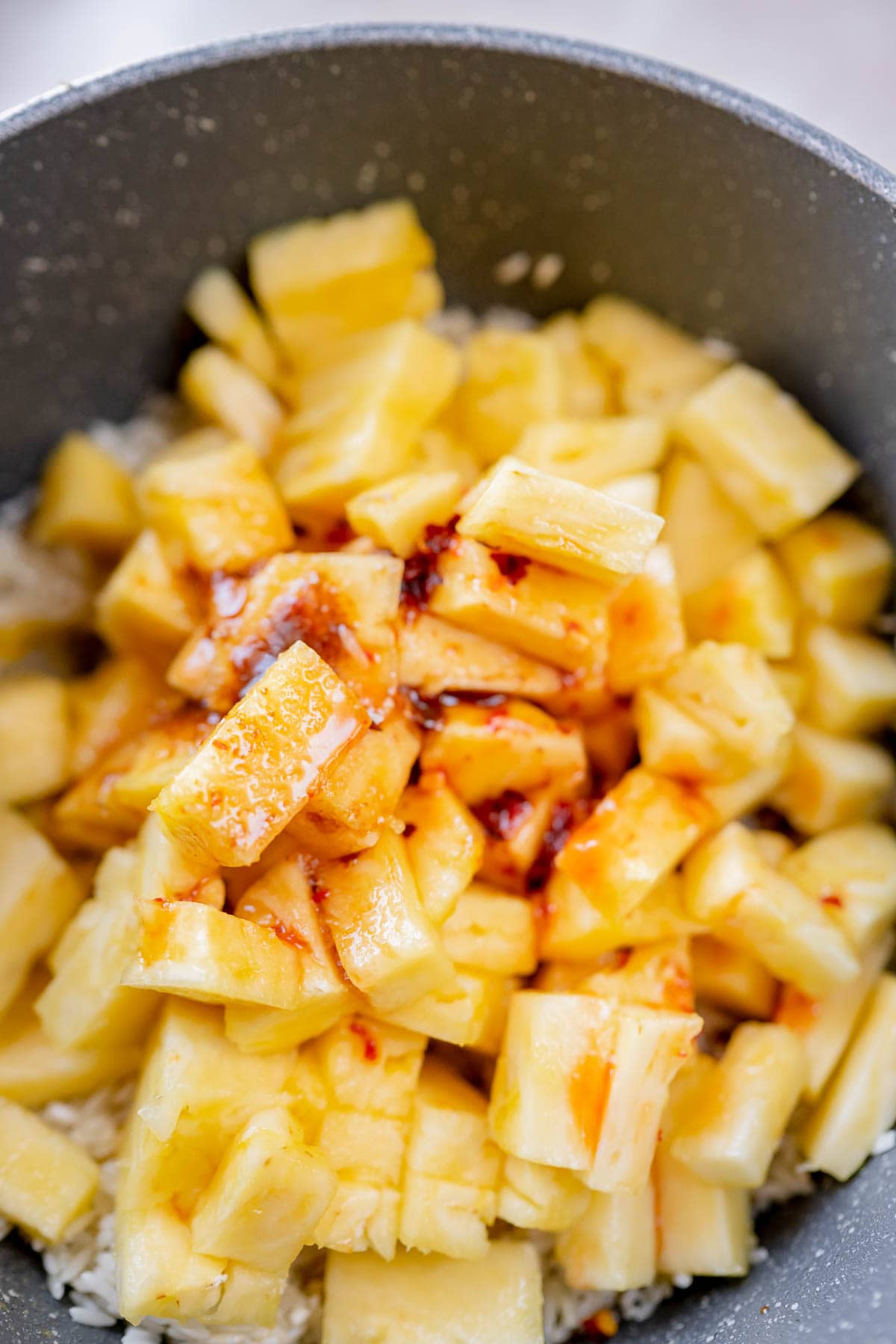 A saucepan of pineapple chunks and spices.