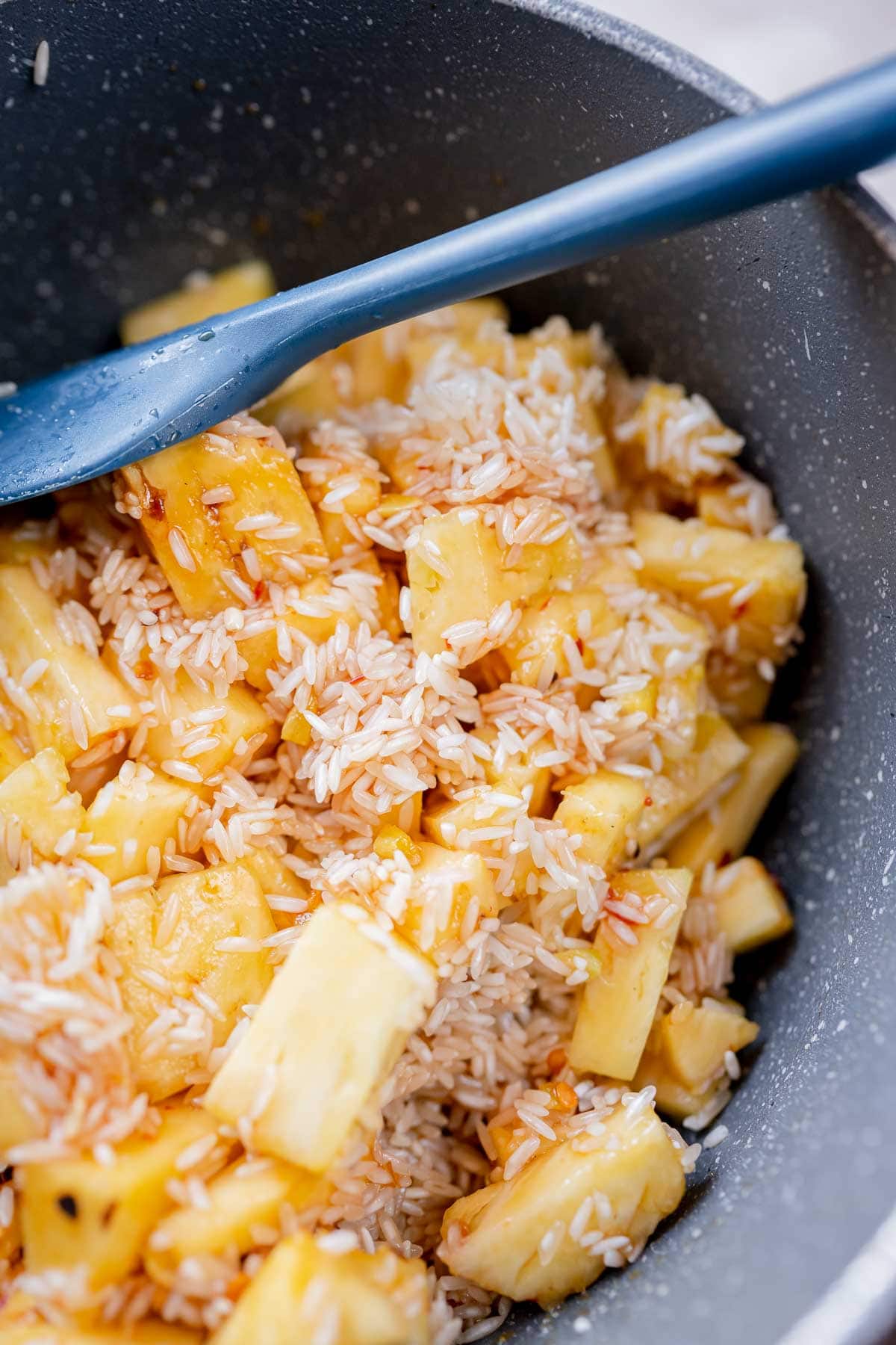 A saucepan filled with pineapple chunks and white rice.