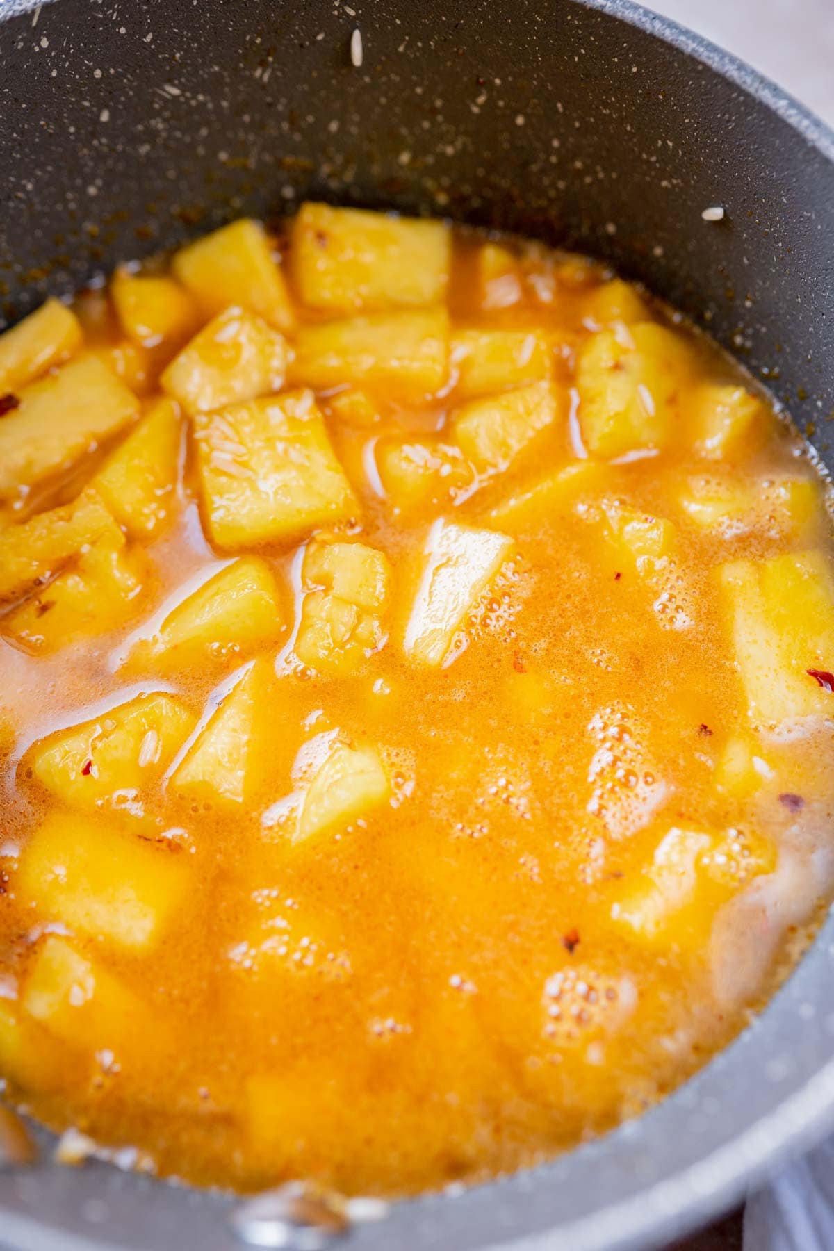A saucepan filled with pineapple chunks and water.