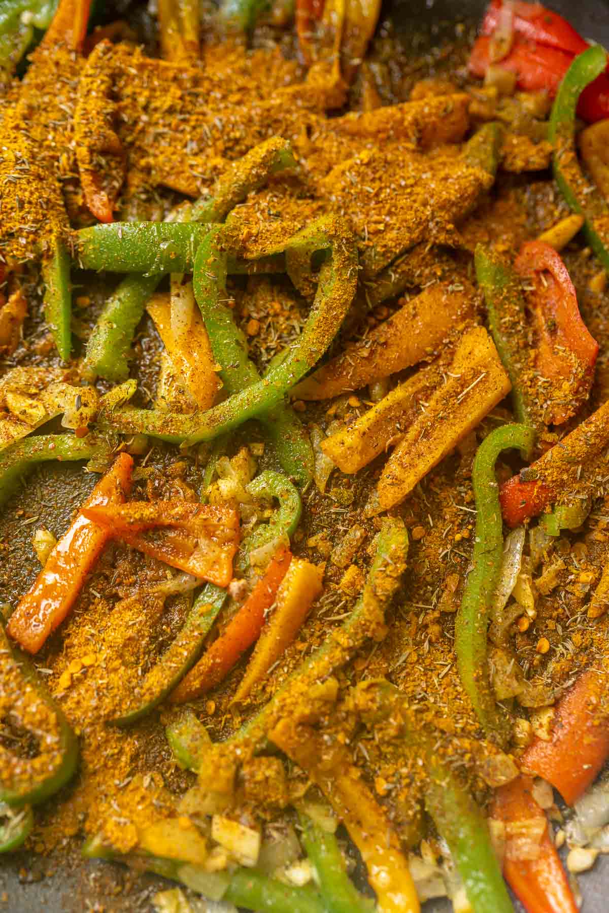 Veggies being sautéed in a pan with spices.