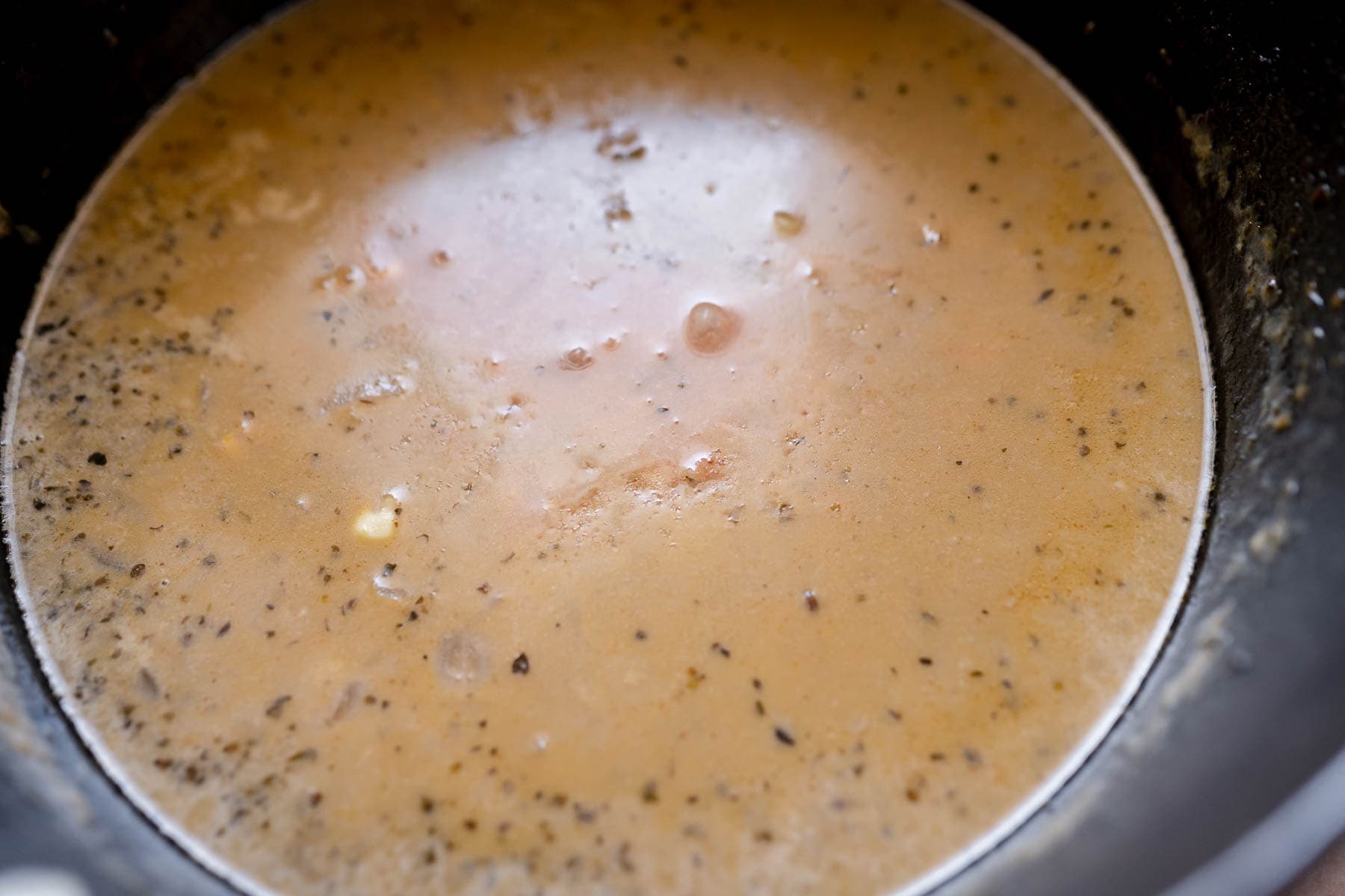 A light brown liquid resting in a large black pot.