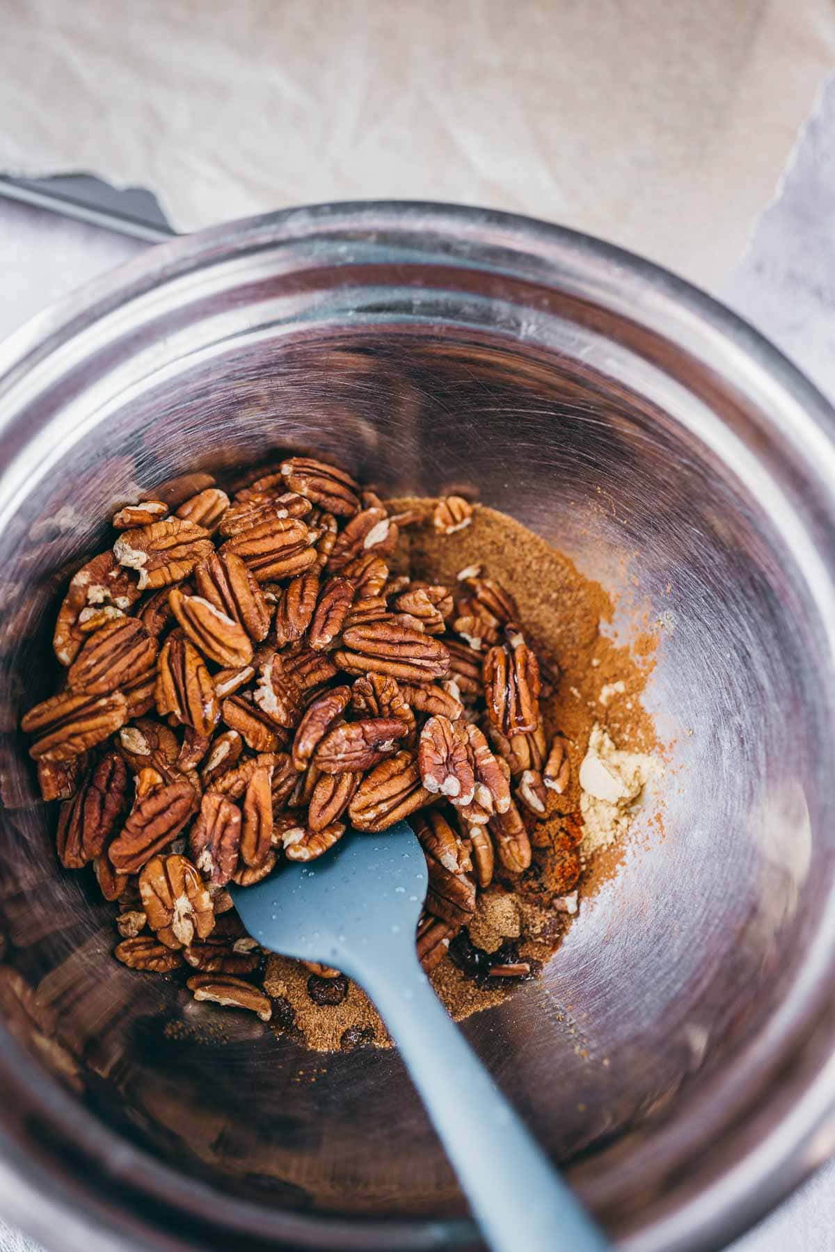 A large mixing bowl filled with spices and raw pecan nuts.