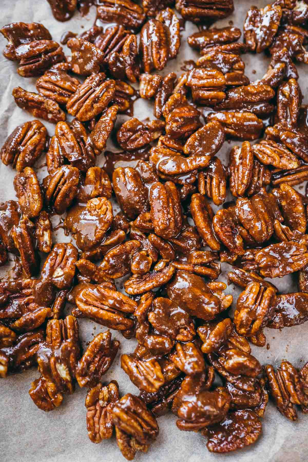 A piece of parchment paper scattered with spicy coated pecan halves.