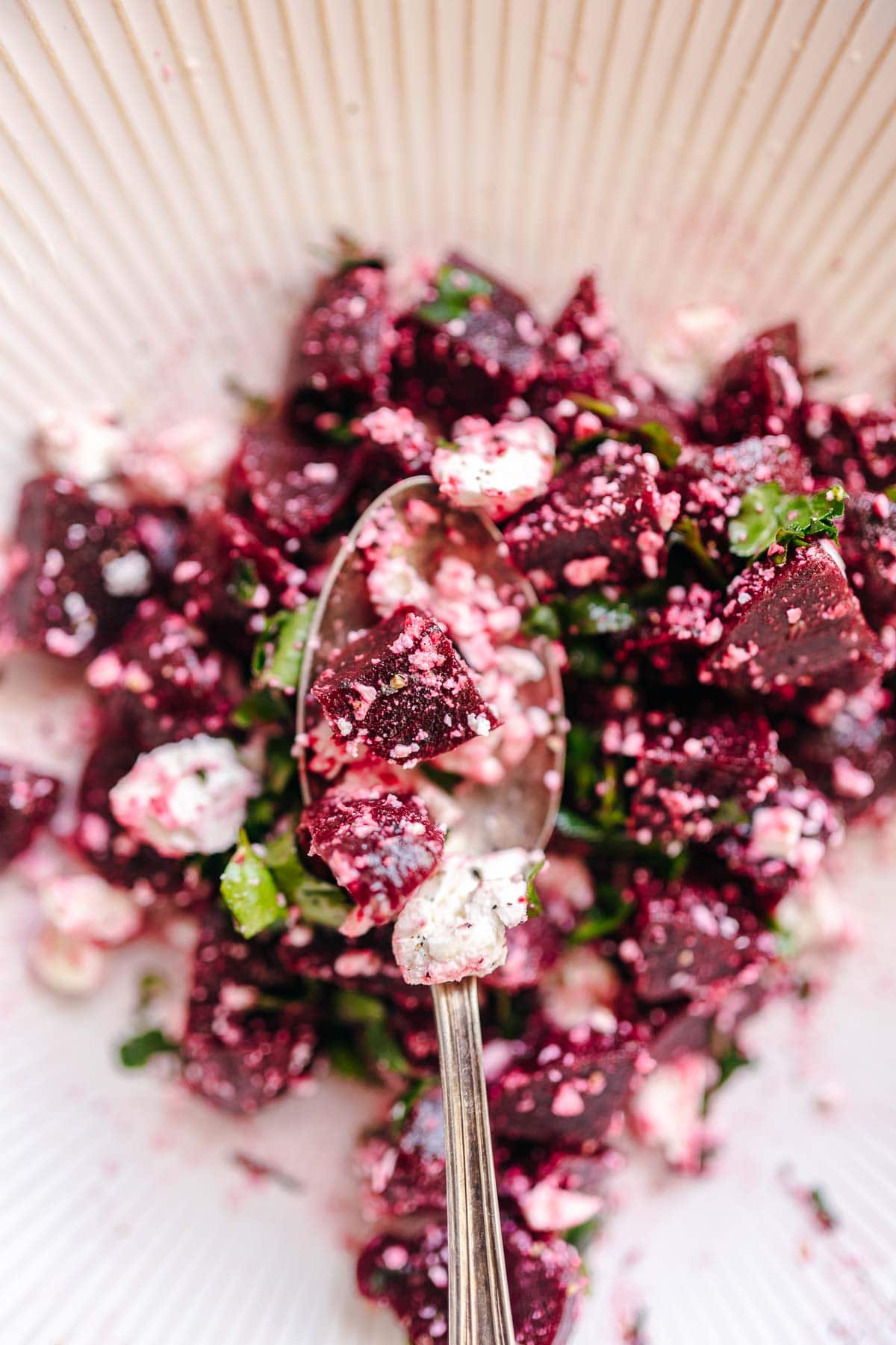 Top view of a silver spoon holding beet feta salad.