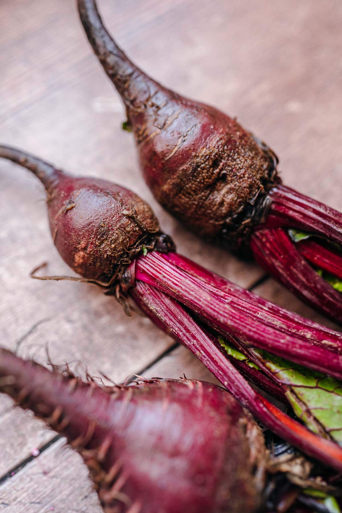 Fresh beets resting on a light wooden table.