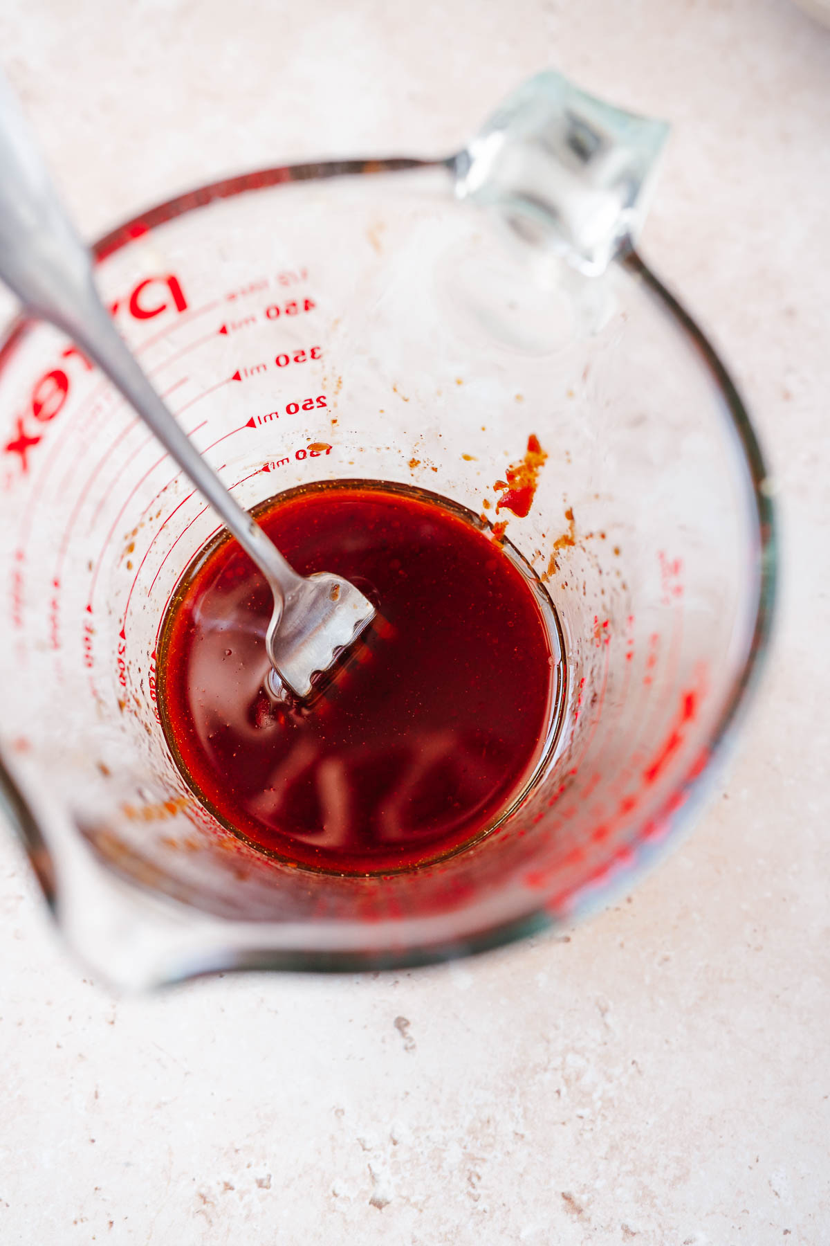 A small glass mixing cup filled with a deep red liquid.