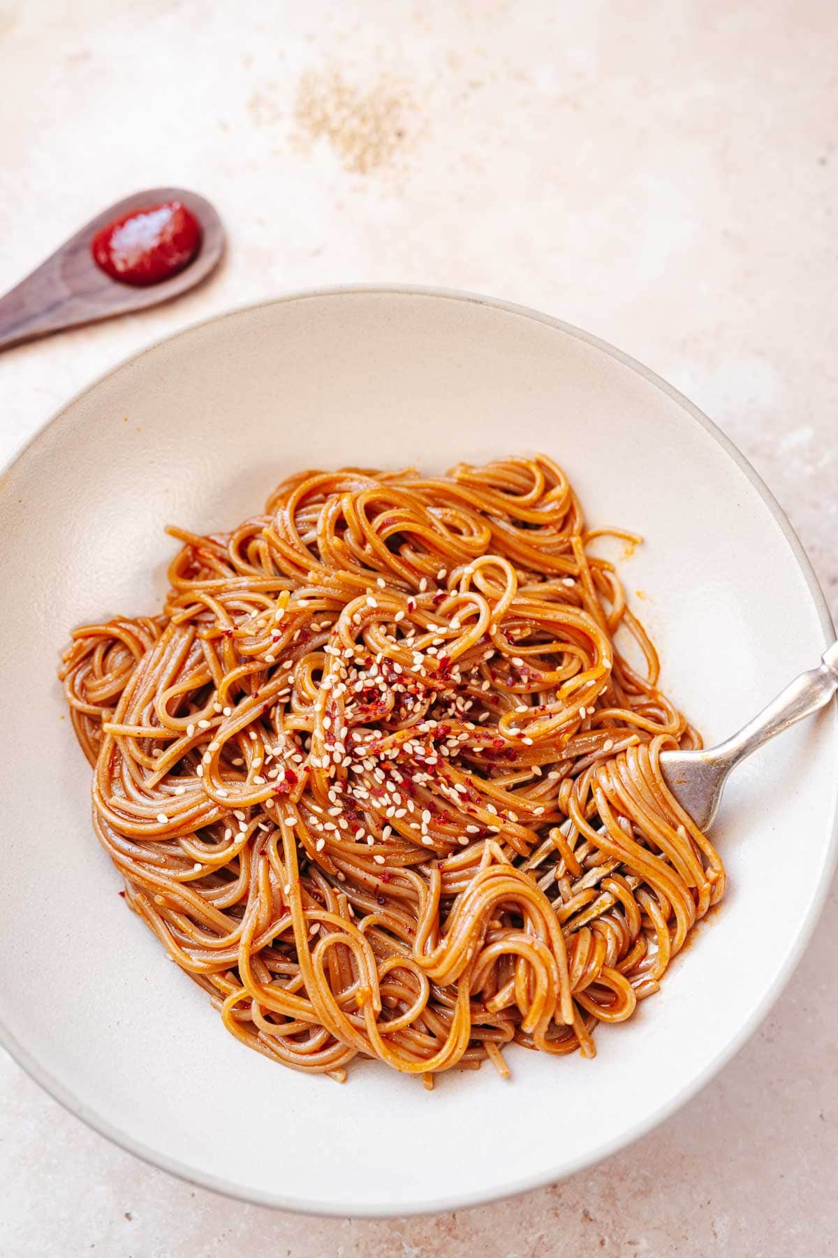 A large ceramic bowl filled with noodles coated in a red sauce.