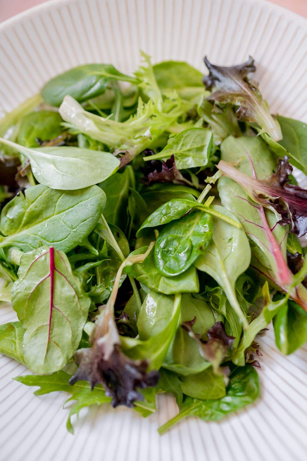 A large white ceramic bowl filled with fresh salad greens.