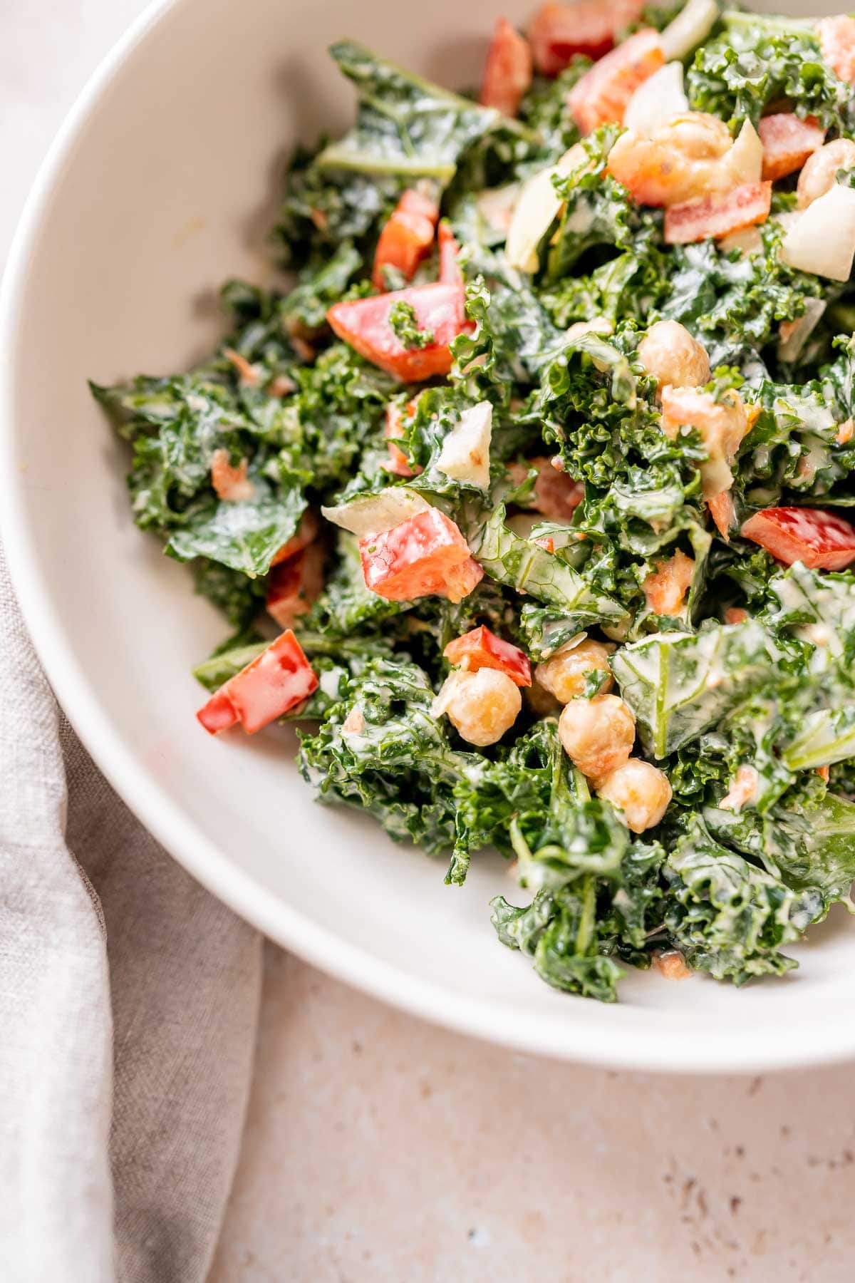 Close view of a delicious tahini kale salad in a large white ceramic bowl.