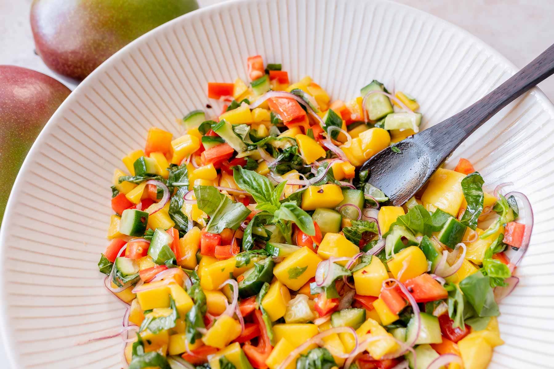 A large ceramic bowl filled with mango salad.