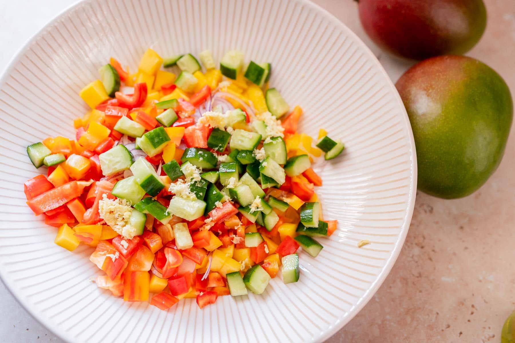 A large bowl filled with chopped fruit and vegetables.
