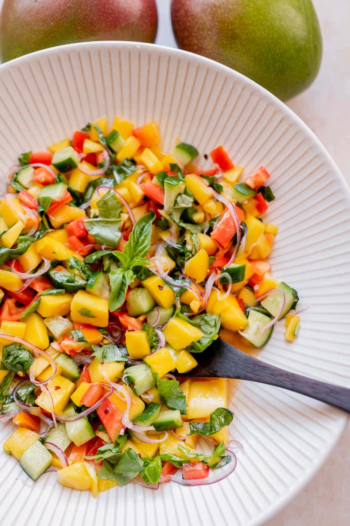 Homemade mango salad in a large striped white ceramic bowl.