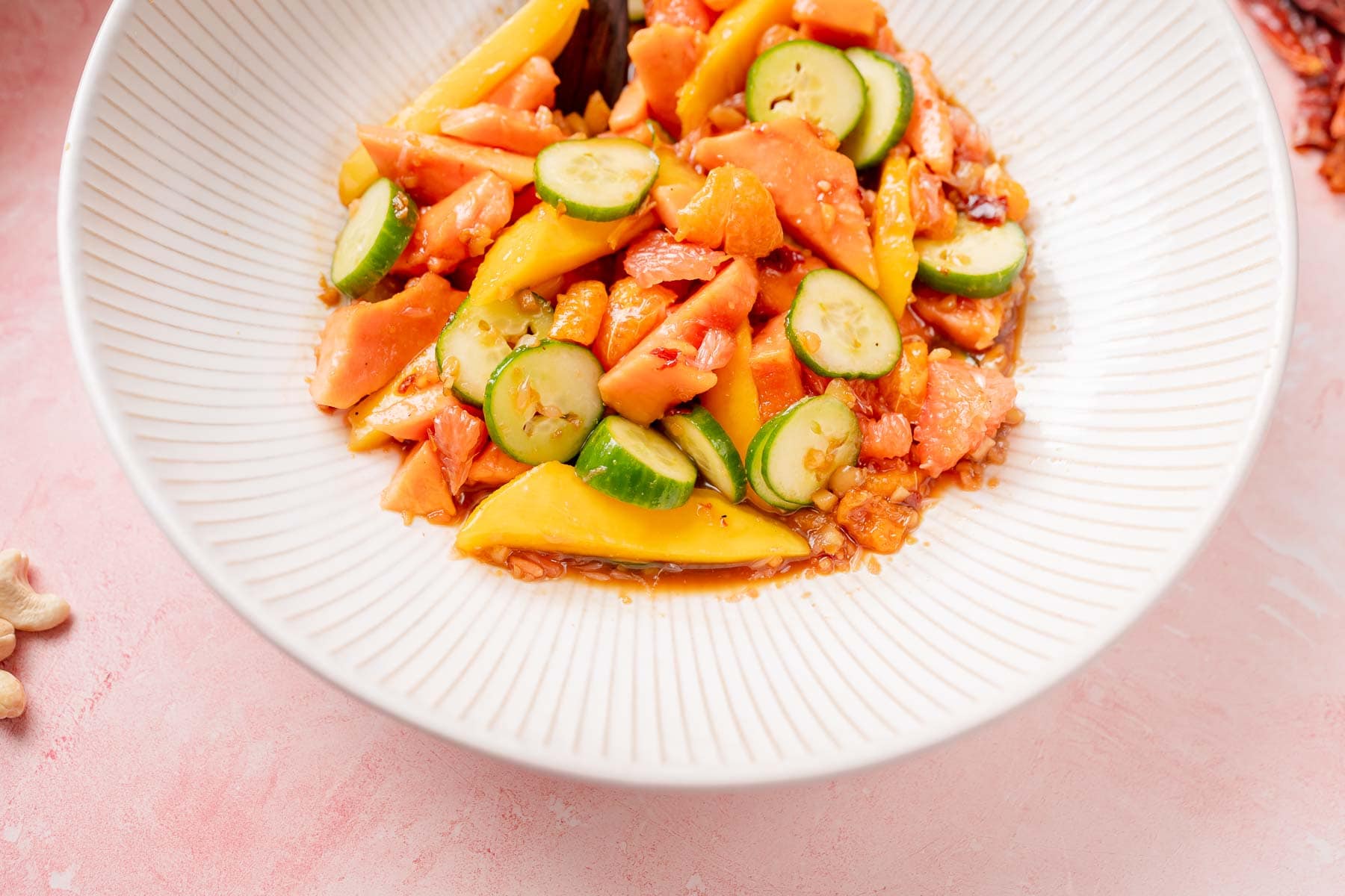 Top view of a mixed fruit salad in a large white ceramic bowl.