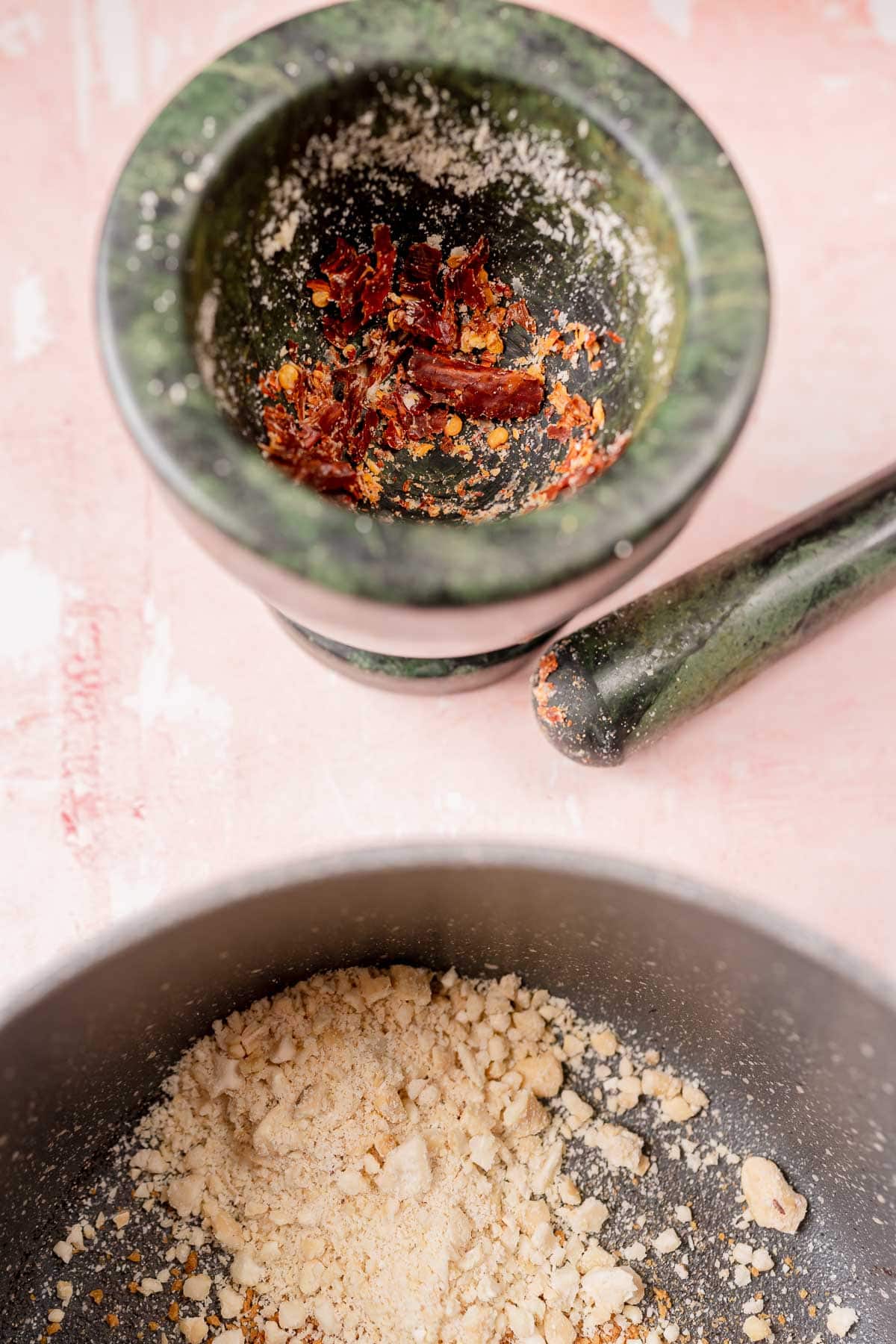 A mortar and pestle filled with crushed dried red chiles.