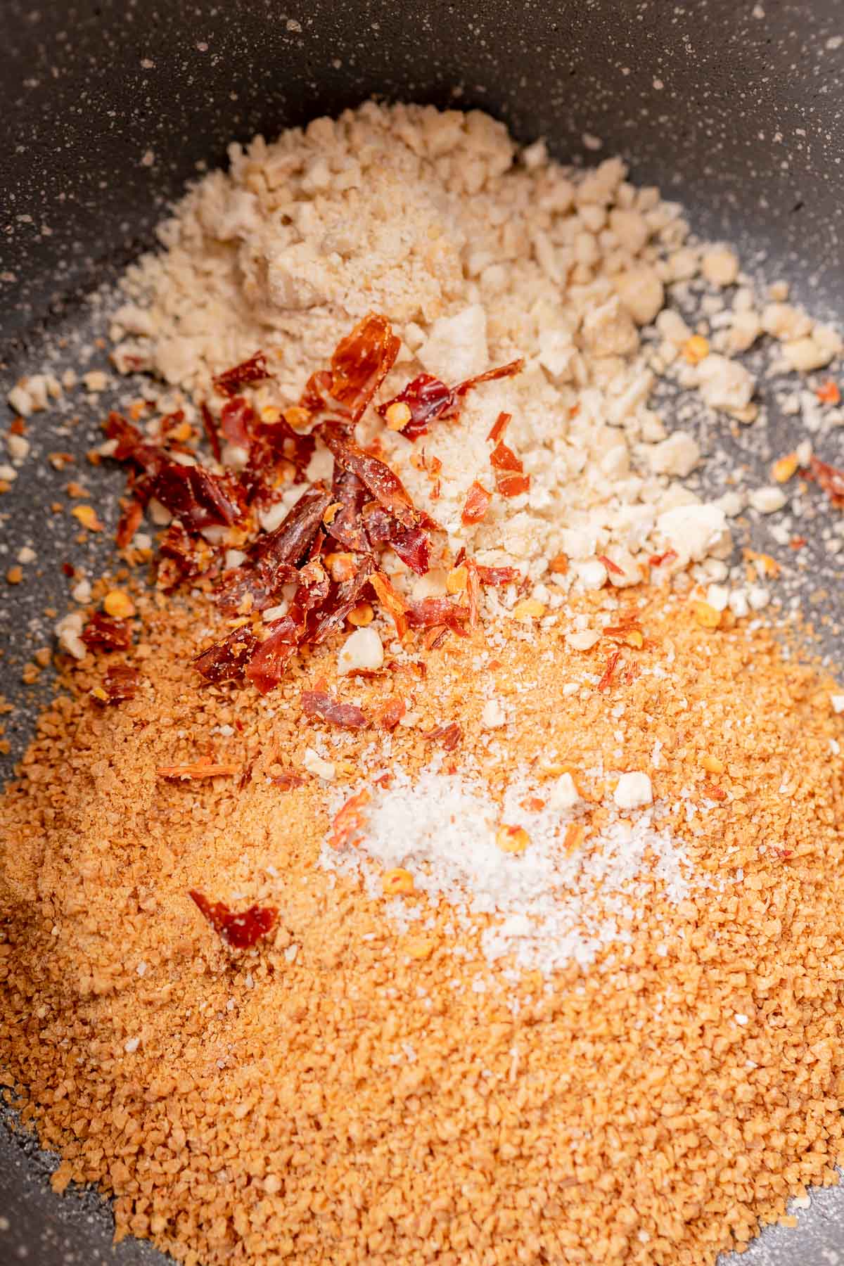 A saucepan filled with sugar, nuts and crushed chilies.