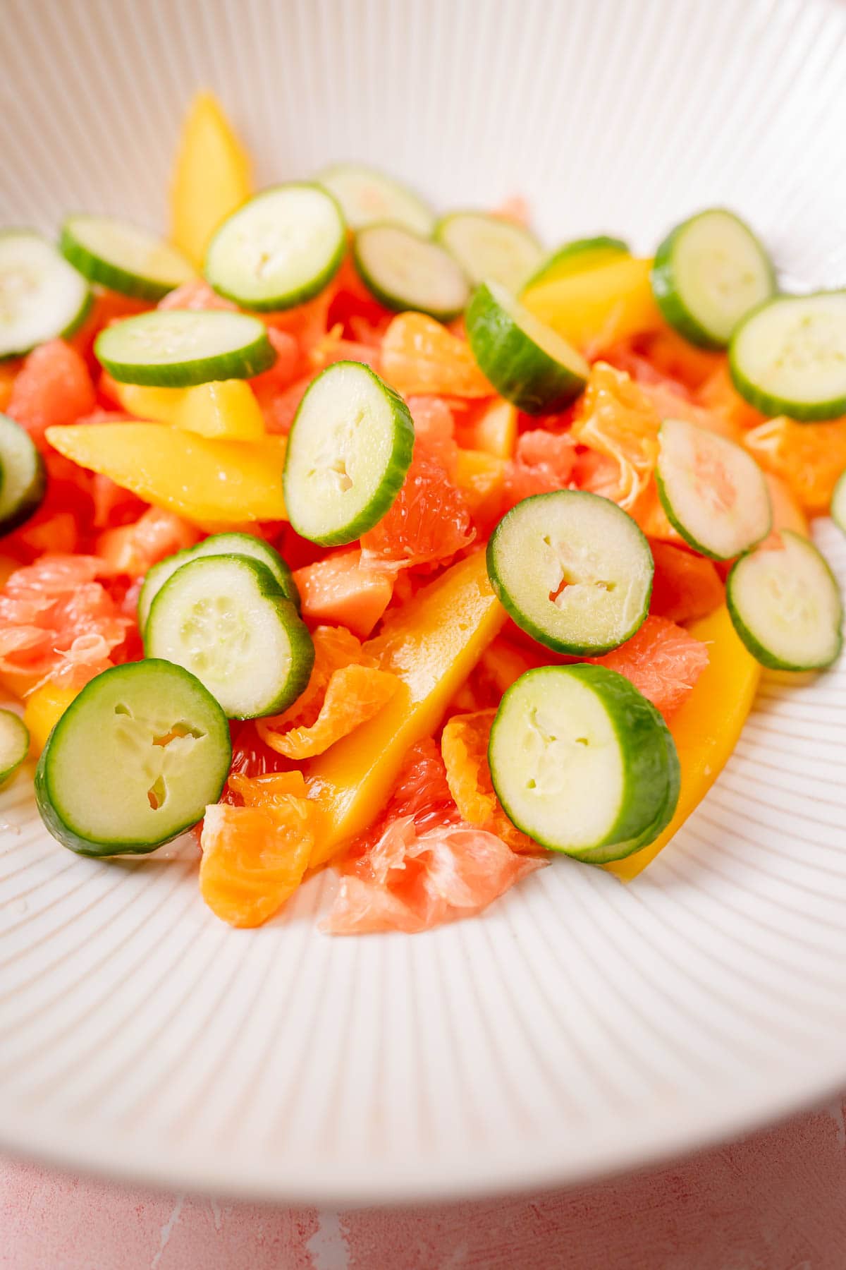 Colorful sliced fruit in a large white bowl.