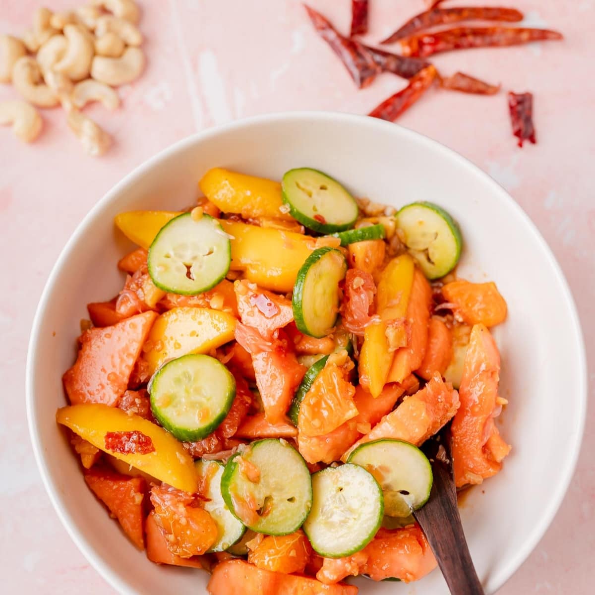 A white bowl filled with a colorful fruit salad.