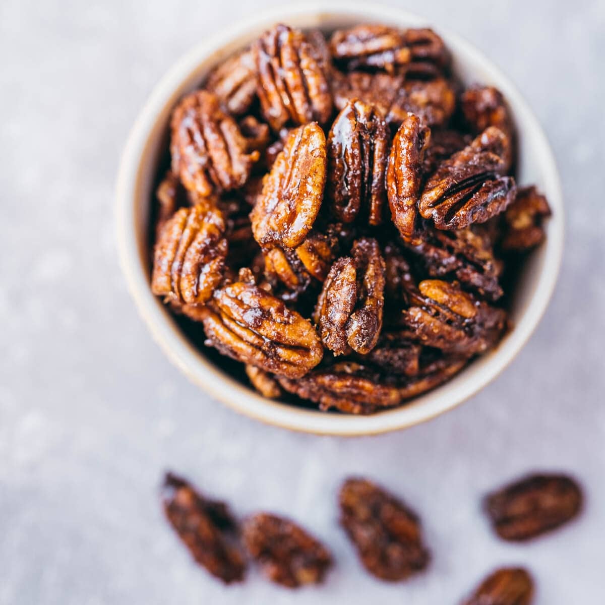 Top view of a small white bowl of candied pecans.