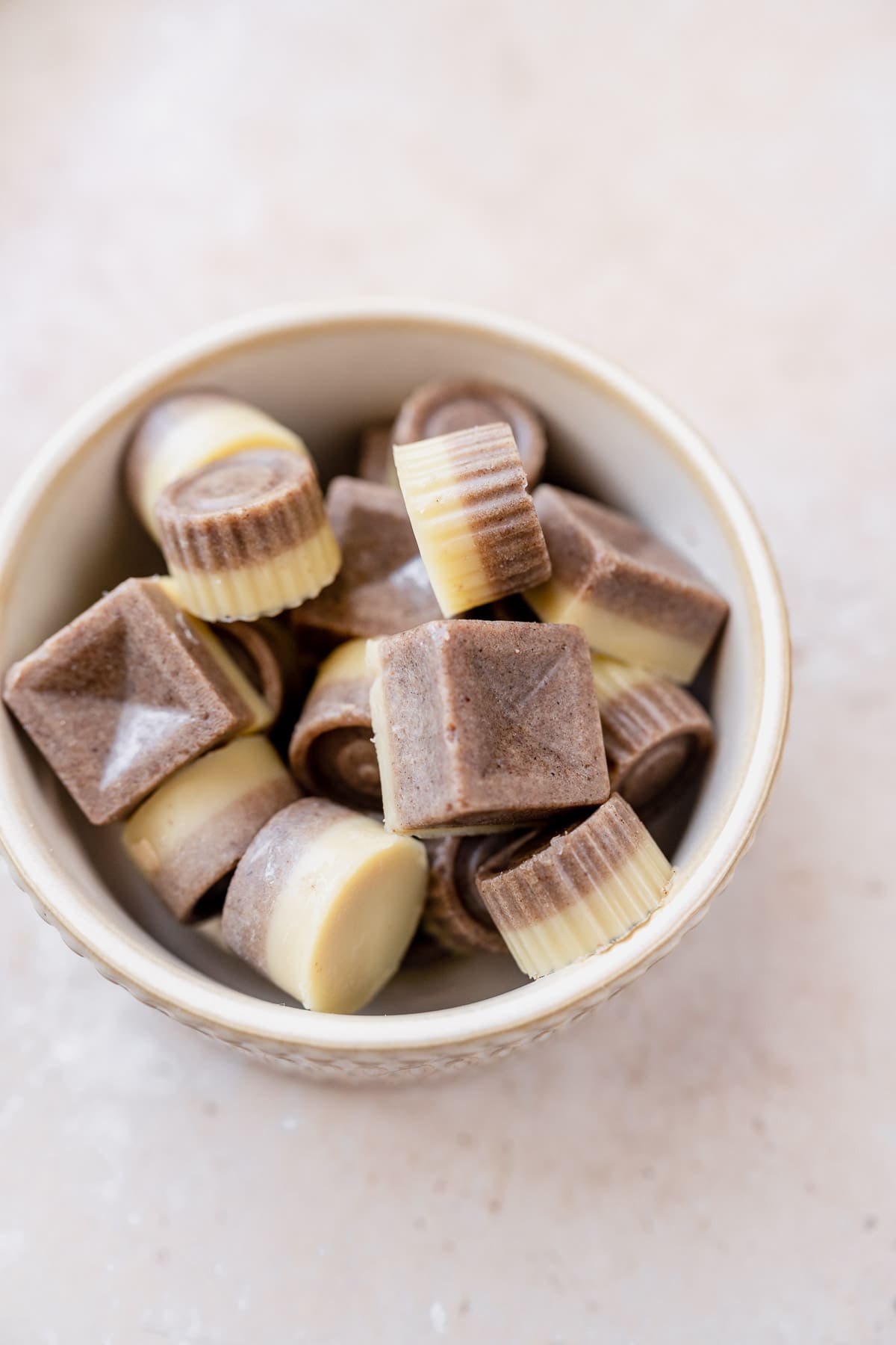 A small ceramic bowl of chai white chocolates piled together.